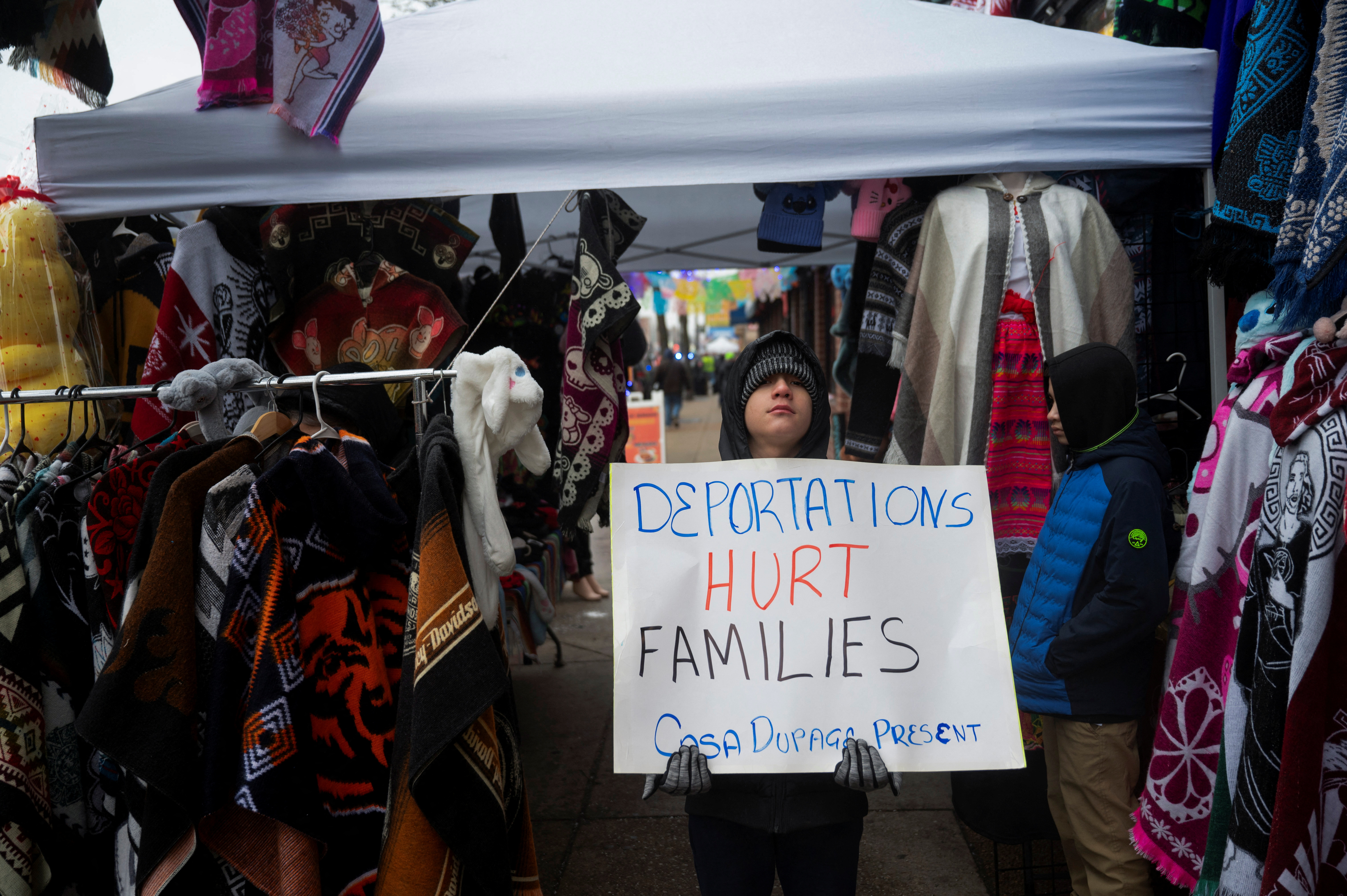 A protester outside in Chicago holds up a sign that reads, "Deportation Hurts Families."