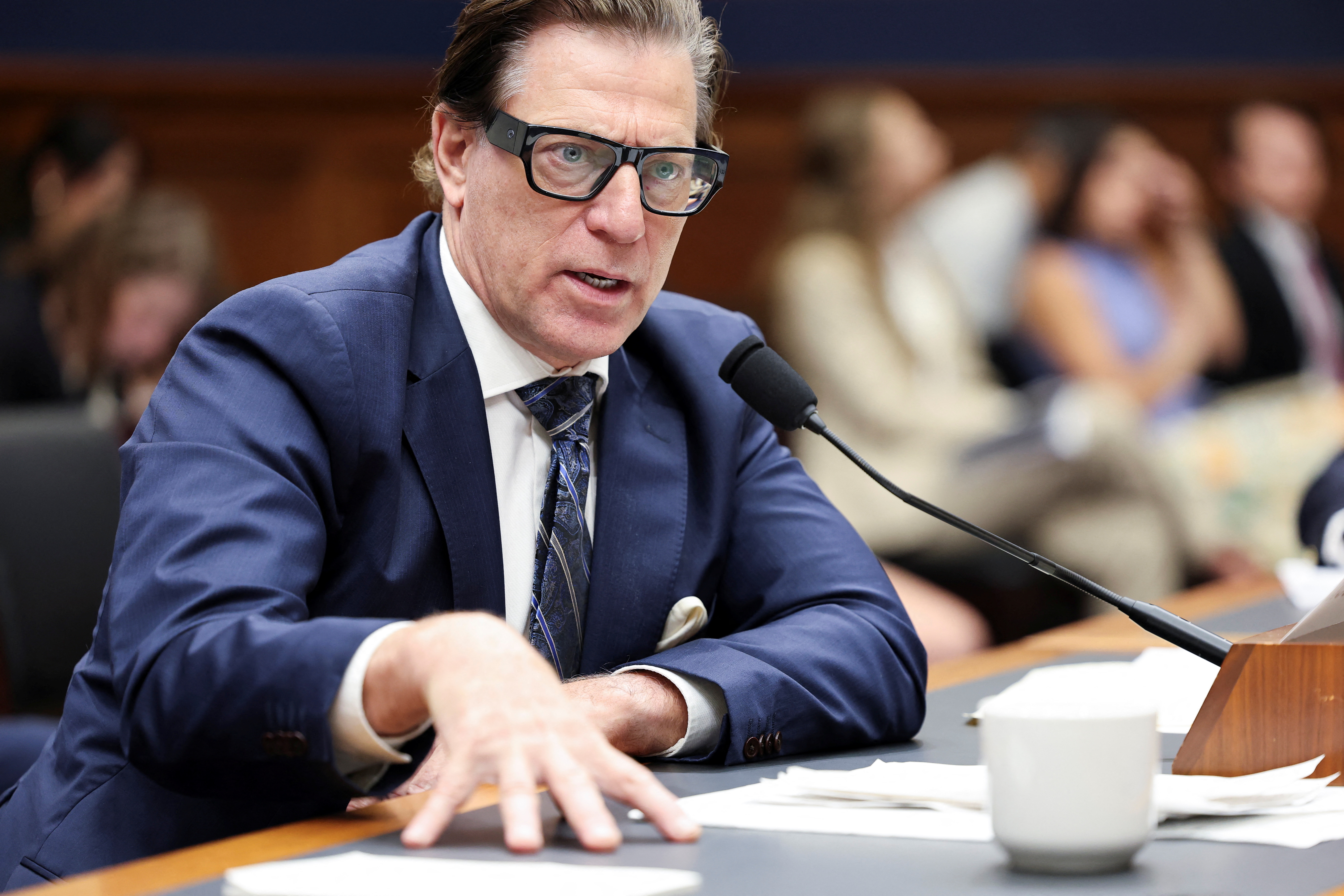 David Richardson of FEMA testifies before a House panel. He places a hand — his fingers spread wide — on the table he's seated at as he speaks into a microphone.