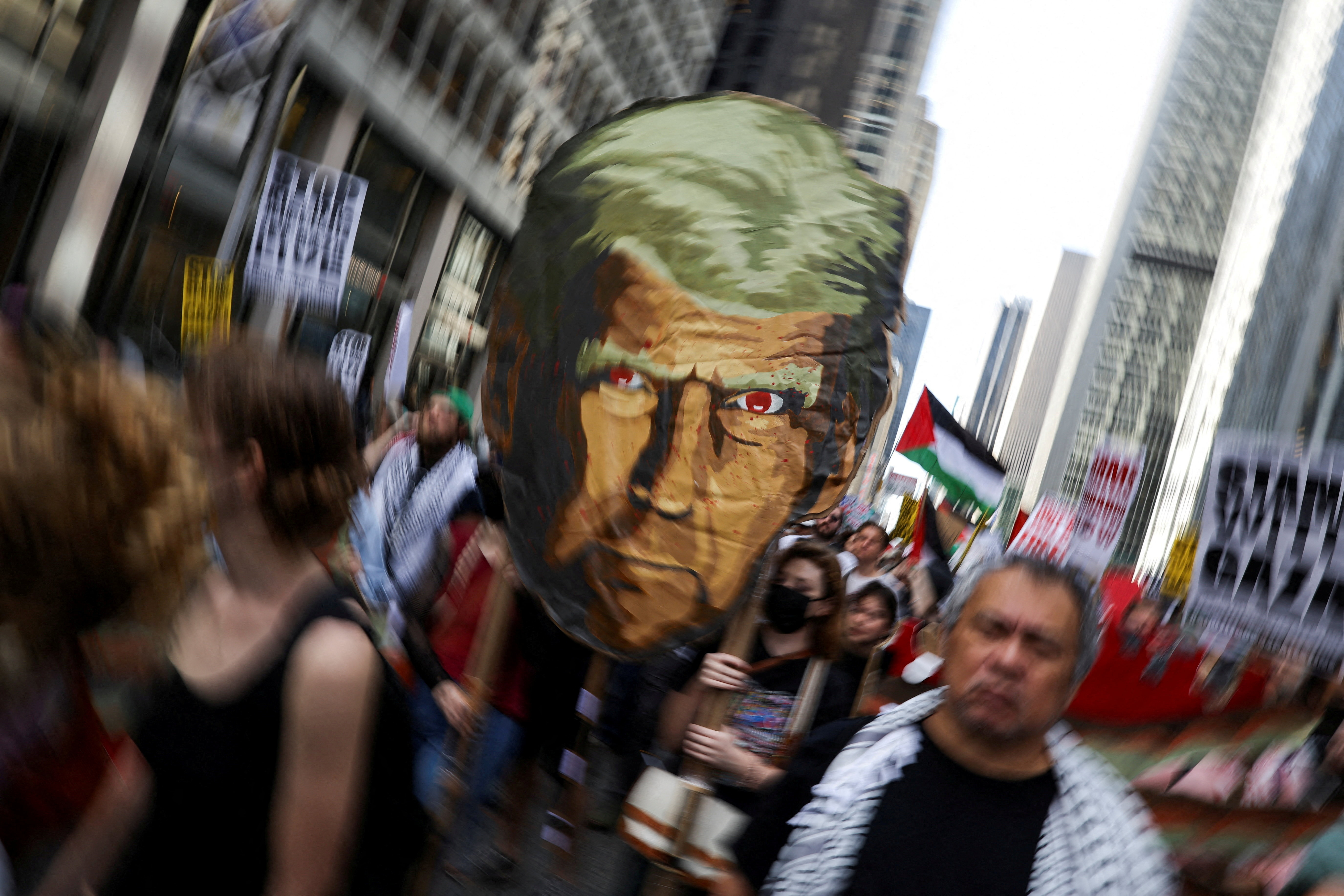 A protester on the streets of New York holds up a picture of Donald Trump's face with red eyes