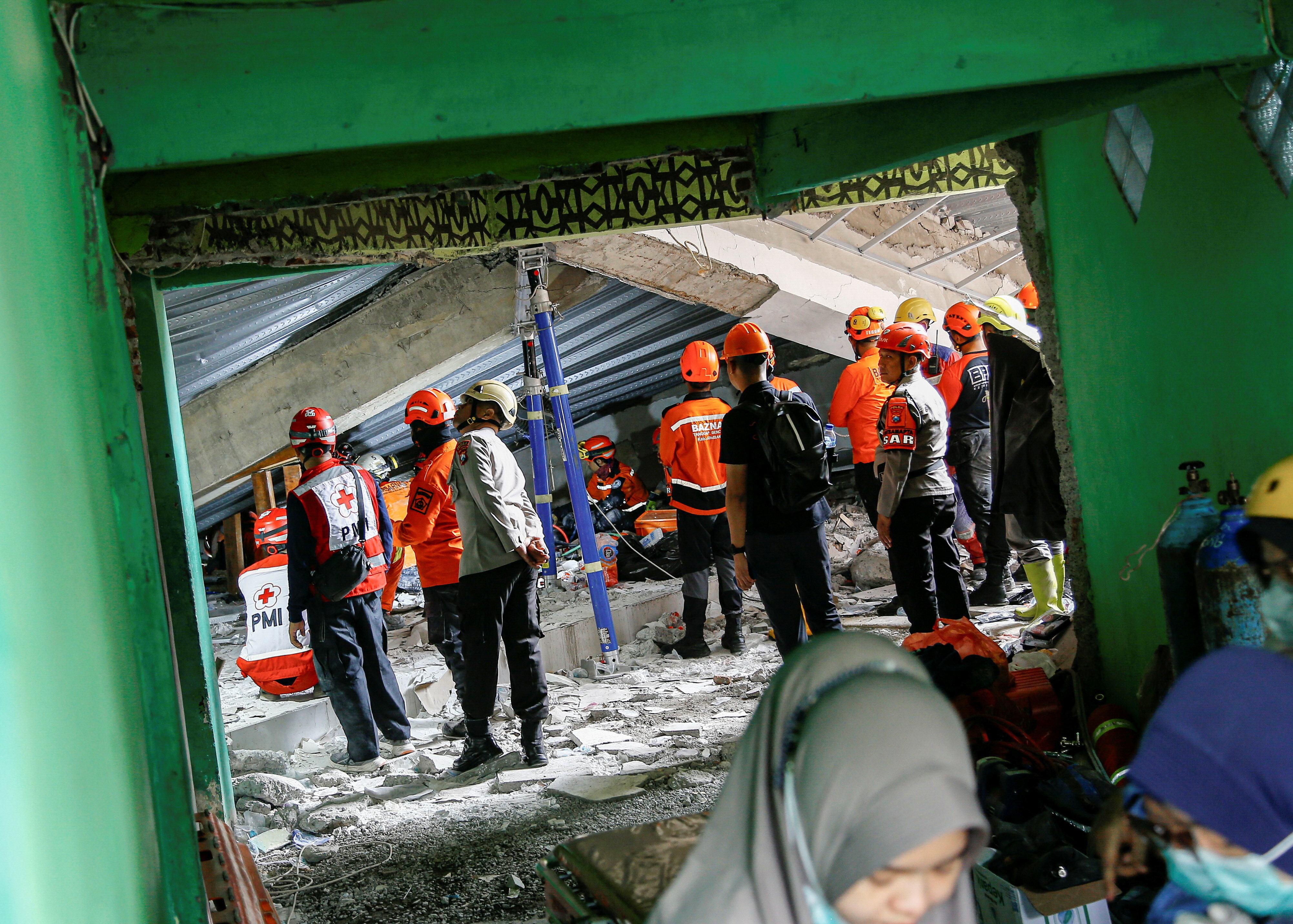 Search and rescue officers stand amid the rubble of a collapsed building, at Al Khoziny Islamic Boarding School in Sidoarjo, East Java, Indonesia