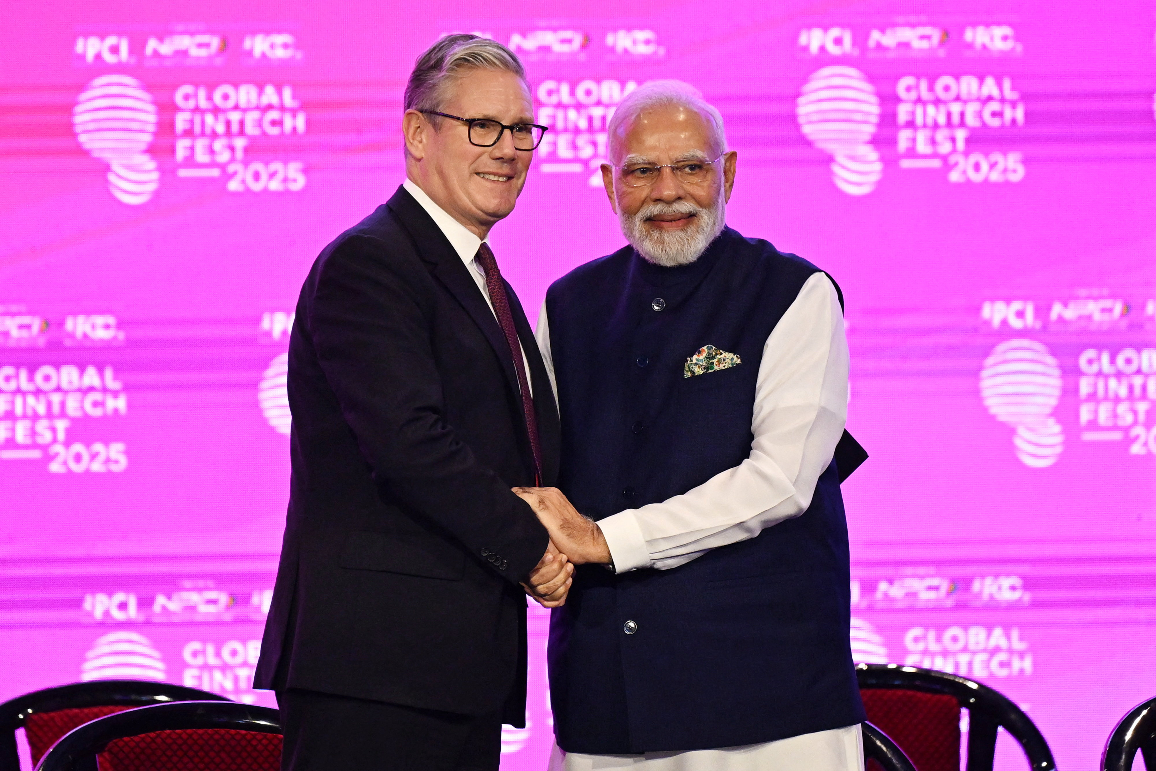 British Prime Minister Keir Starmer and Prime Minister of India Narendra Modi shake hands while smiling at the camera.