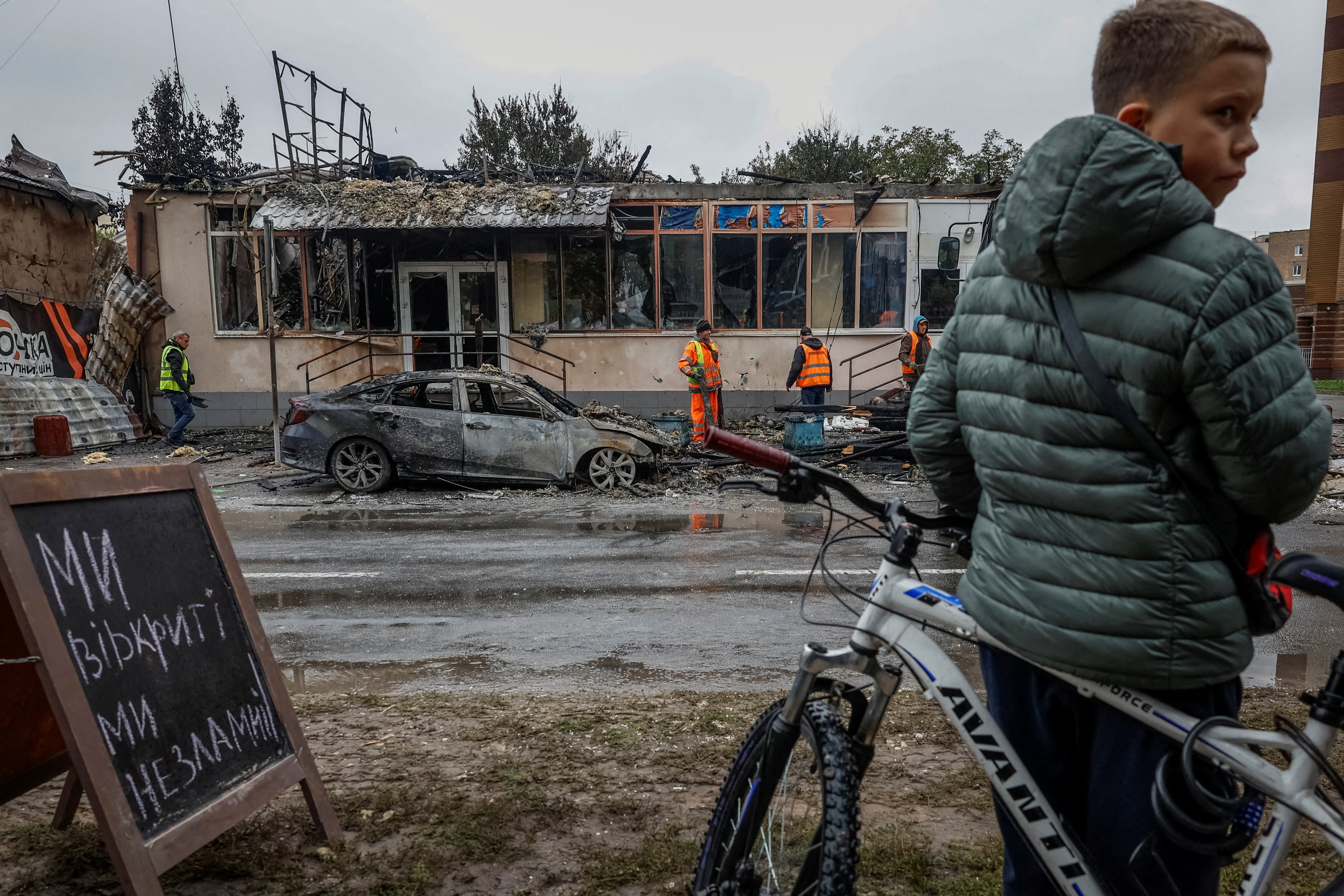 A boy with a bicycle looks on near buildings damaged during a Russian drone and missile strike amid Russia's attack on Ukraine, in the town of Brovary, outside of Kyiv, October 10, 2025. REUTERS/Alina Smutko TPX IMAGES OF THE DAY