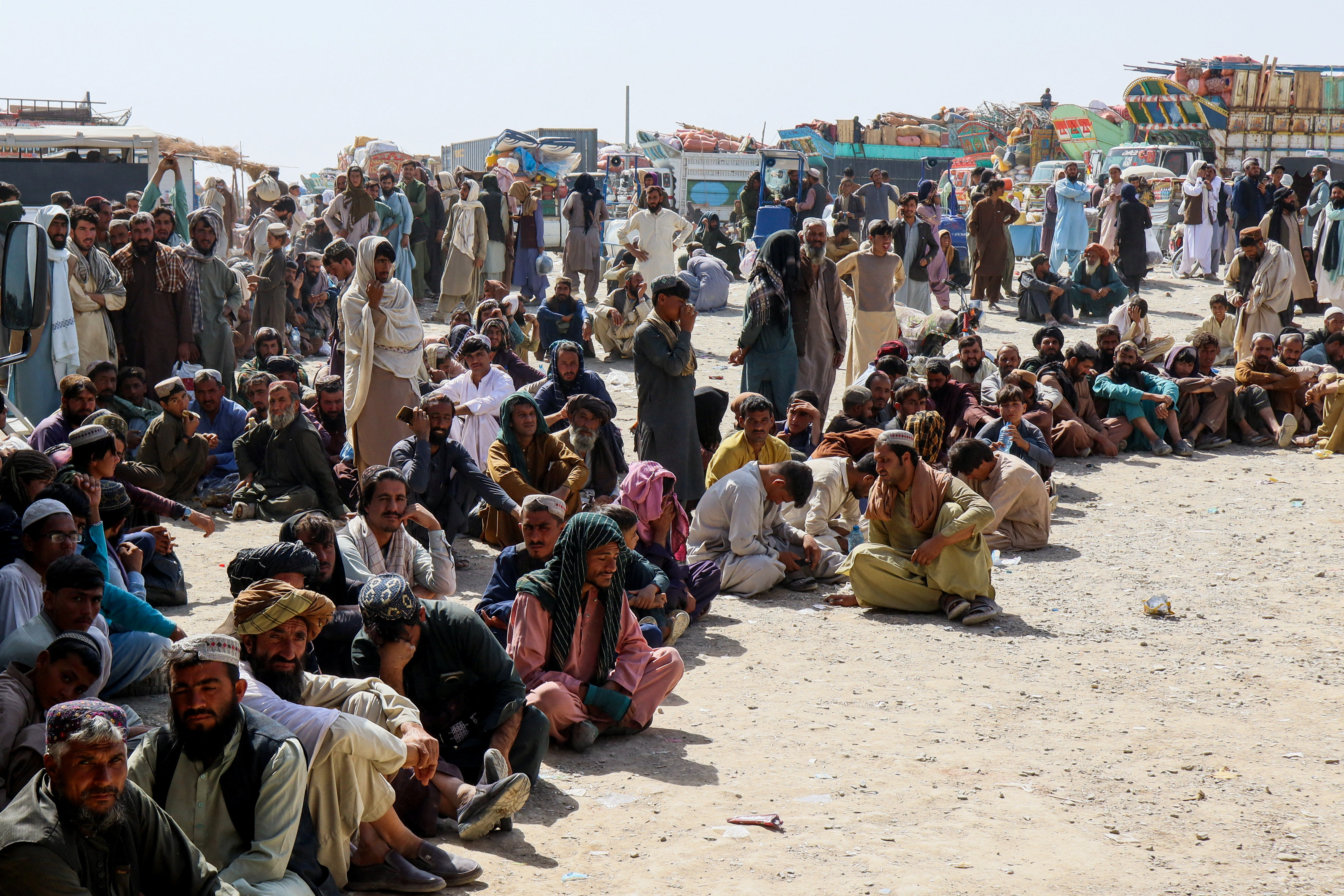 Afghan citizens wait to register to return home as trucks loaded with their belongings stand in the background, after Pakistan closed border crossings for trade with Afghanistan following cross-border clashes between the two countries&rsquo; forces [Saeed Ali Achakzai/Reuters]