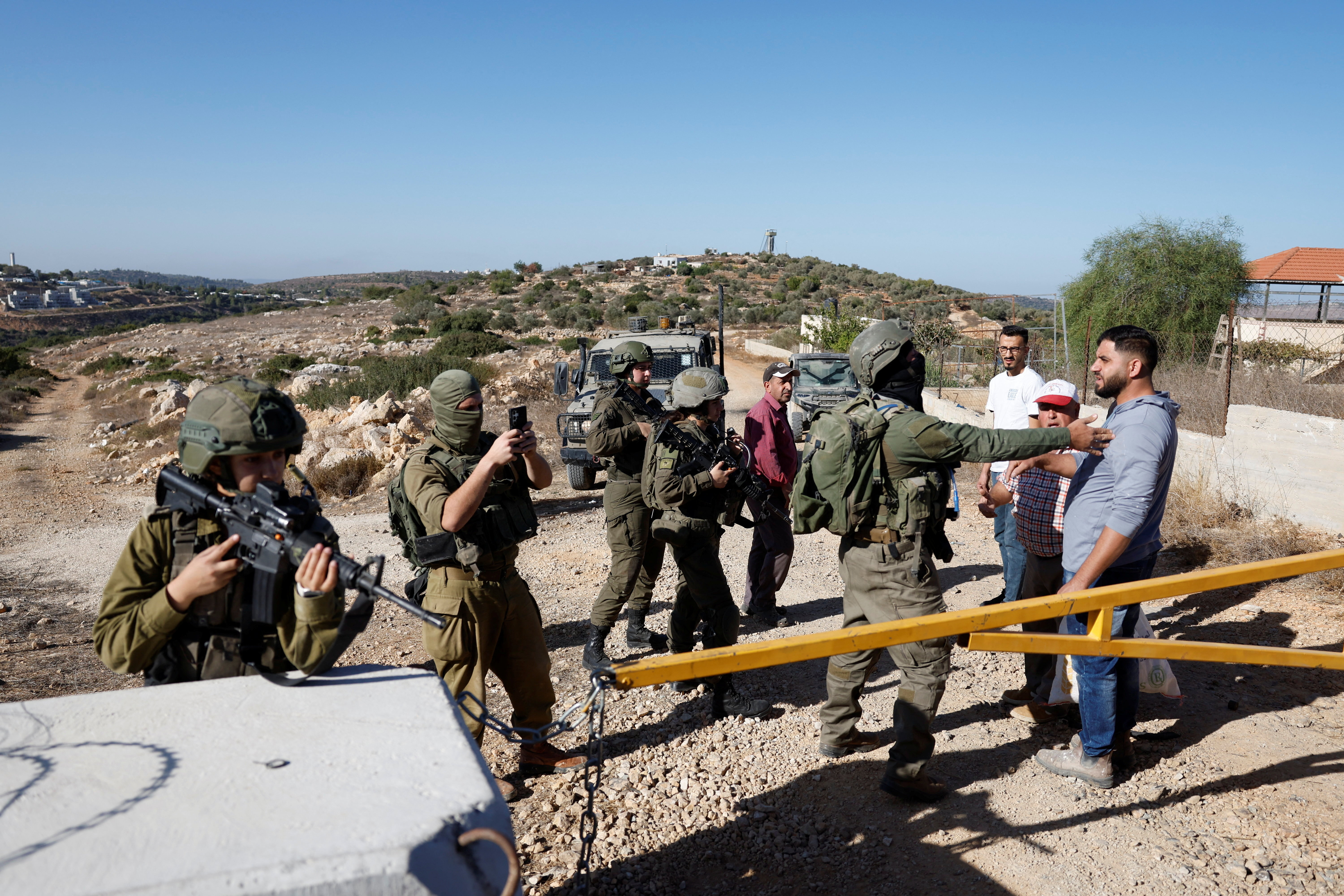 Members of the Israeli forces stand guard near a closed gate during the olive harvest