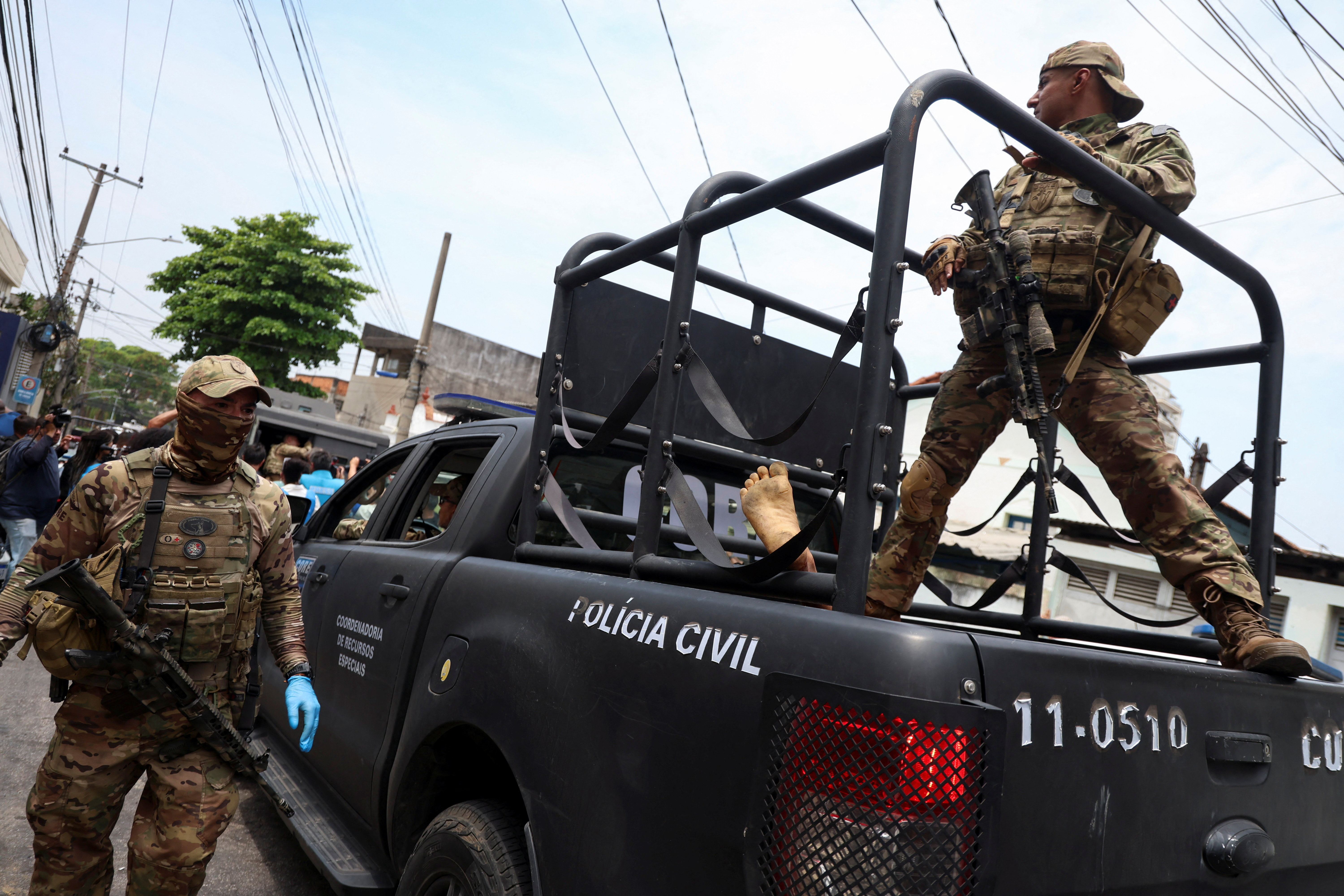 A member of the tactical police unit stands on a vehicle during a police operation against drug trafficking at the favela do Penha [Aline Massuca/Reuters]