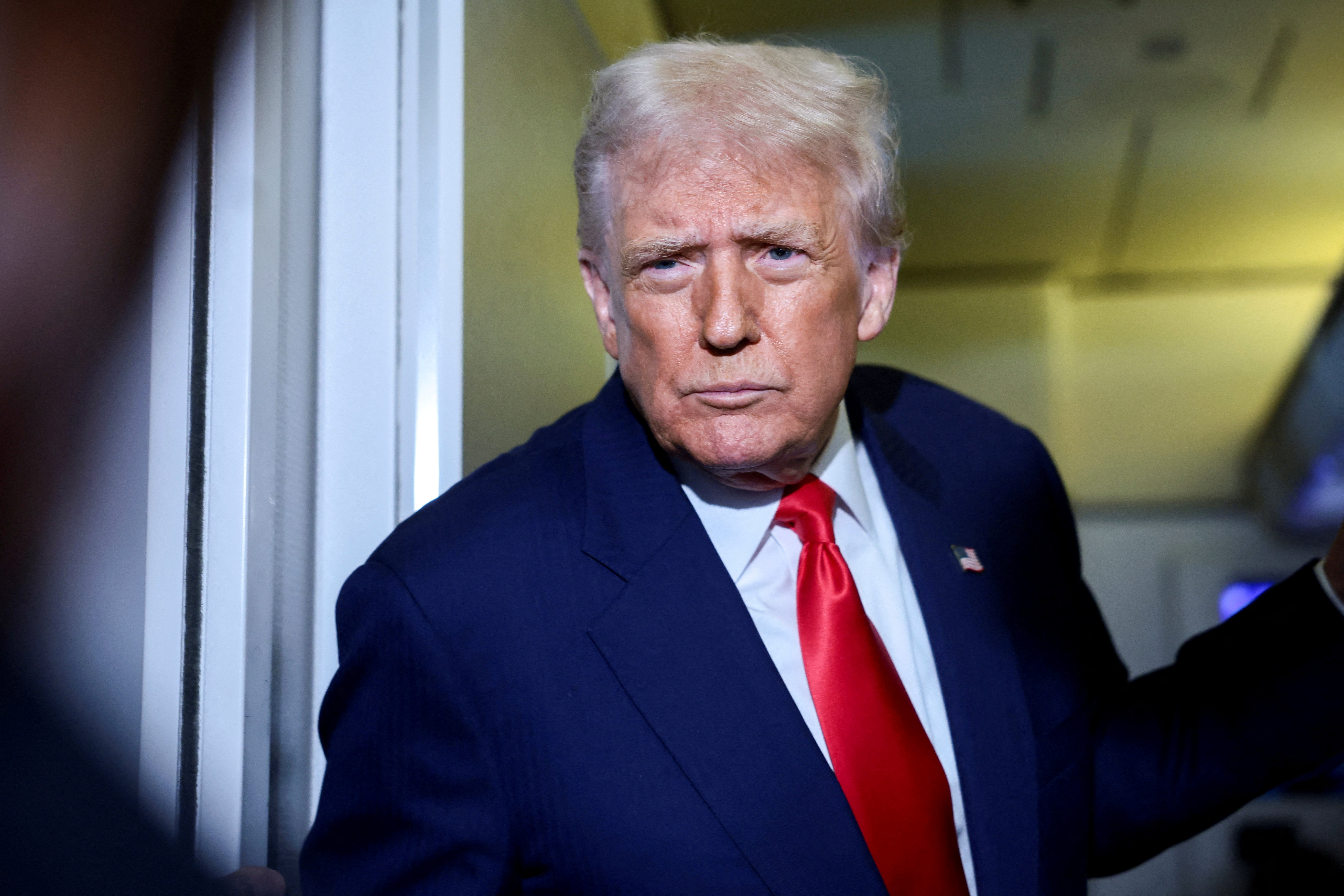 US President Donald Trump speaks to members of the media on board Air Force One