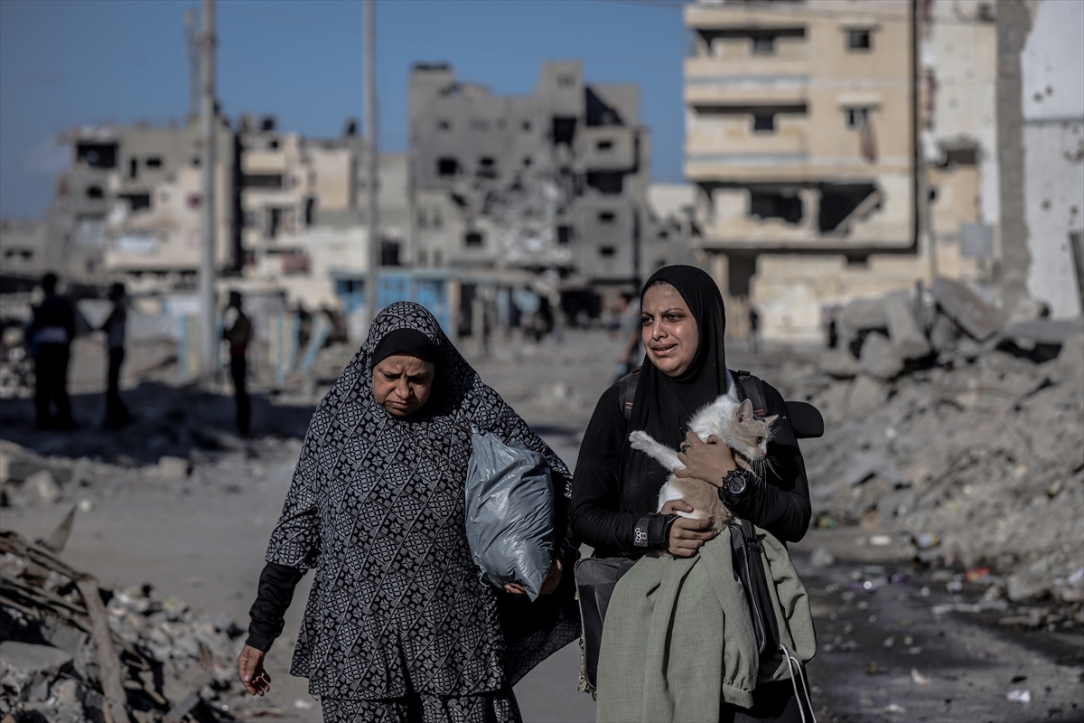 two women walk past destroyed buildings in Gaza