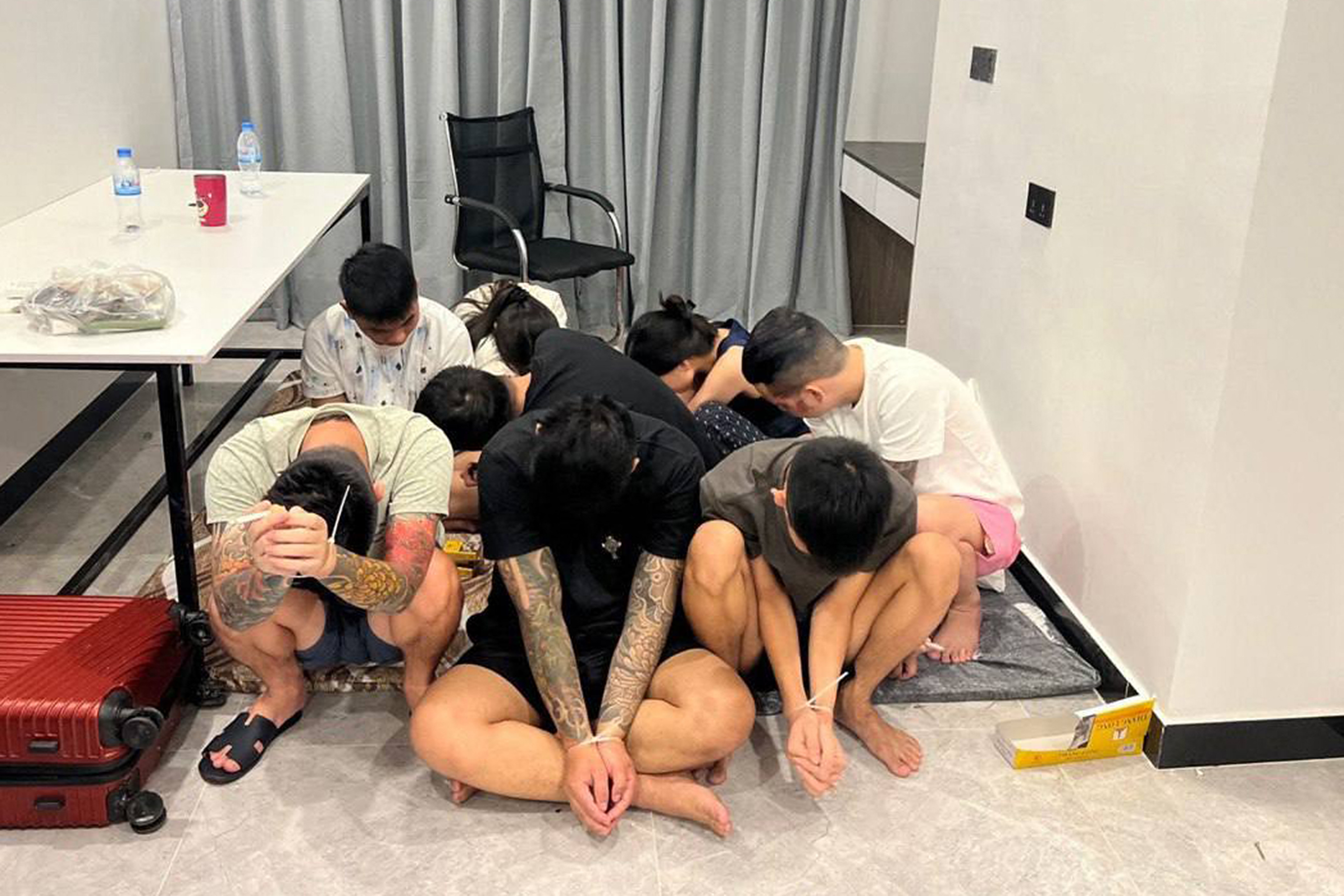 suspects with their hands ziptied after being detained during a raid on a scam centre in Phnom Penh, Cambodia in July
