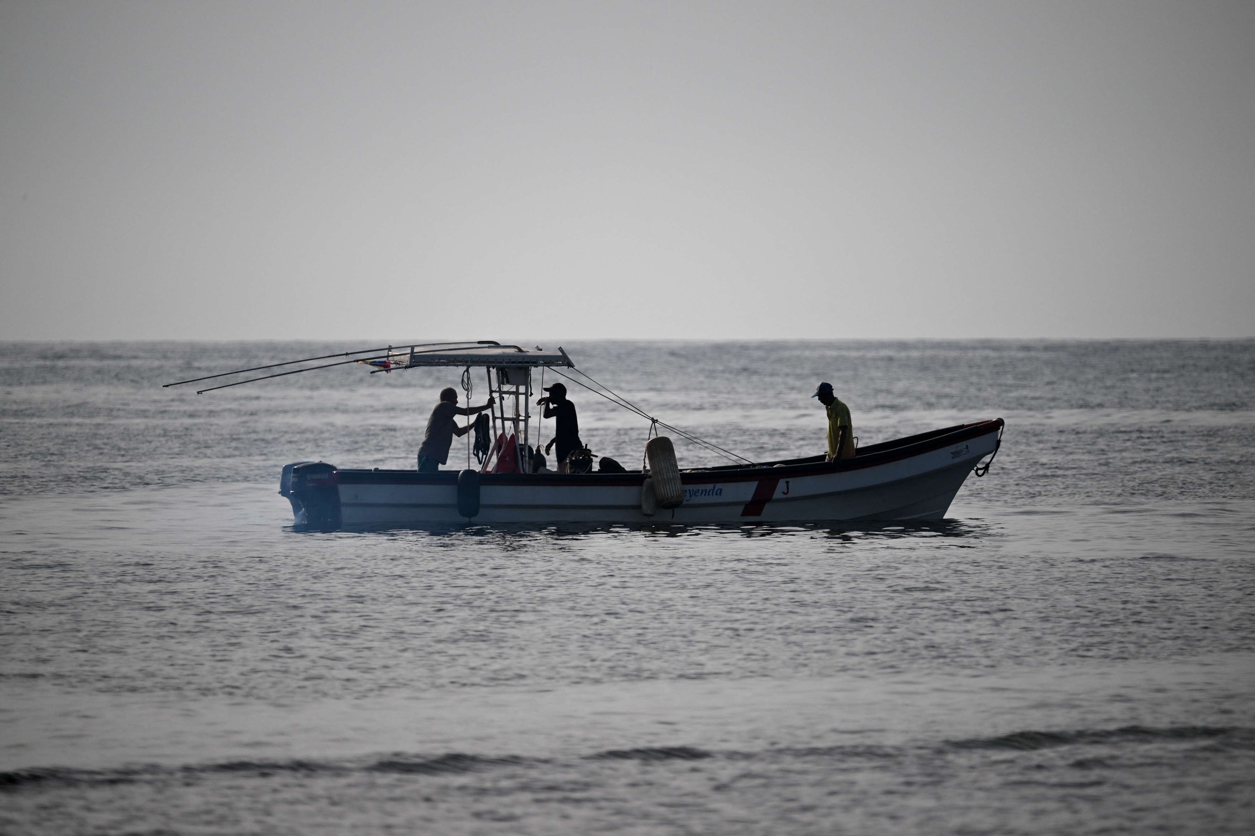 Fishermen sail on a boat near Caraballeda, La Guaira State, Venezuela on September 24, 2025. Venezuelan fishermen take precautions in response to the United States military deployment in the Caribbean, which has left destroyed boats belonging to alleged drug traffickers. (Photo by Federico PARRA / AFP)