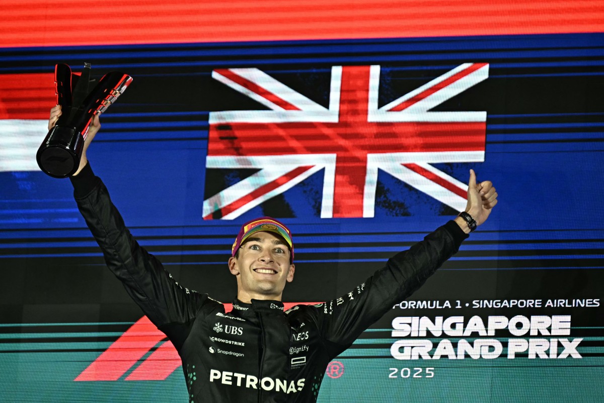 Mercedes race car driver George Russell celebrates on the podium after winning the Singapore Grand Prix at the Marina Bay Street Circuit in Singapore [Lillian Suwanrumpha/AFP]