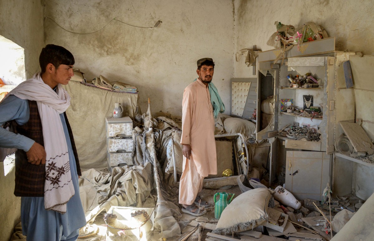 Afghan men inspect a damaged house.