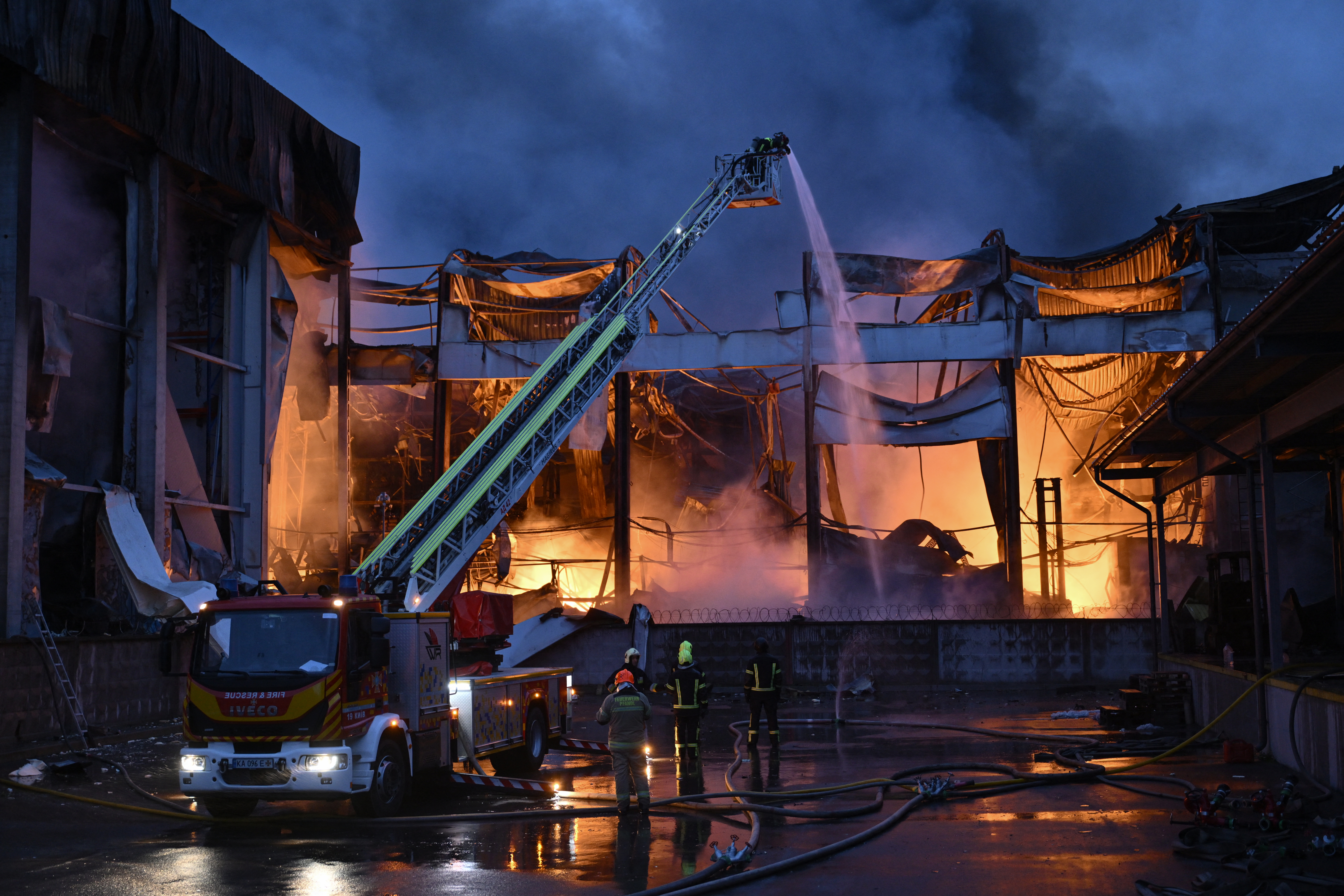 Ukrainian firefighters extinguish a fire at the site of a food warehouse following a Russian missile strike in Kyiv