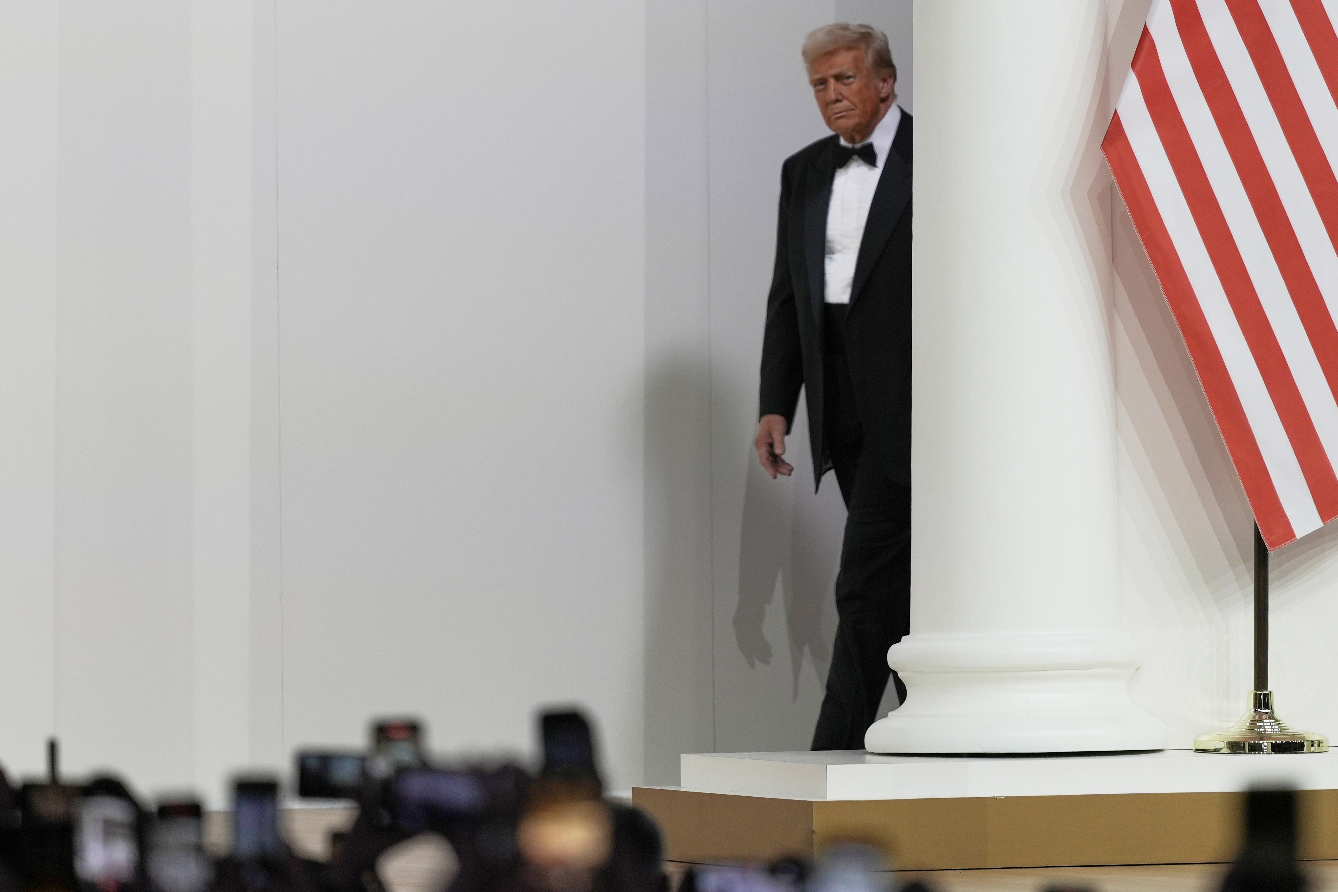 Donald Trump walks out from behind a white column.