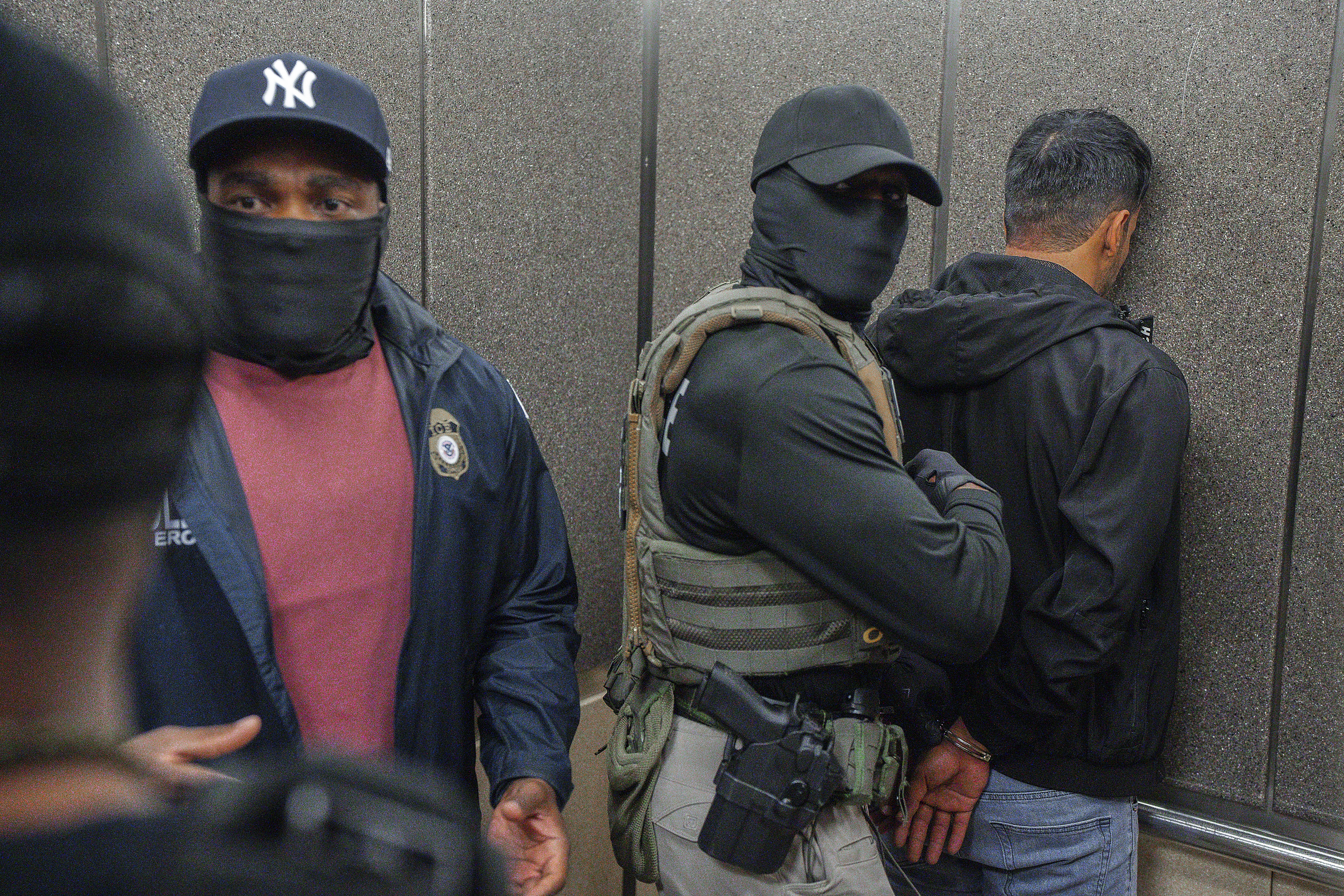 Immigration and Customs Enforcement agents escort a detaining migrants. [File: Olga Fedorova/AP