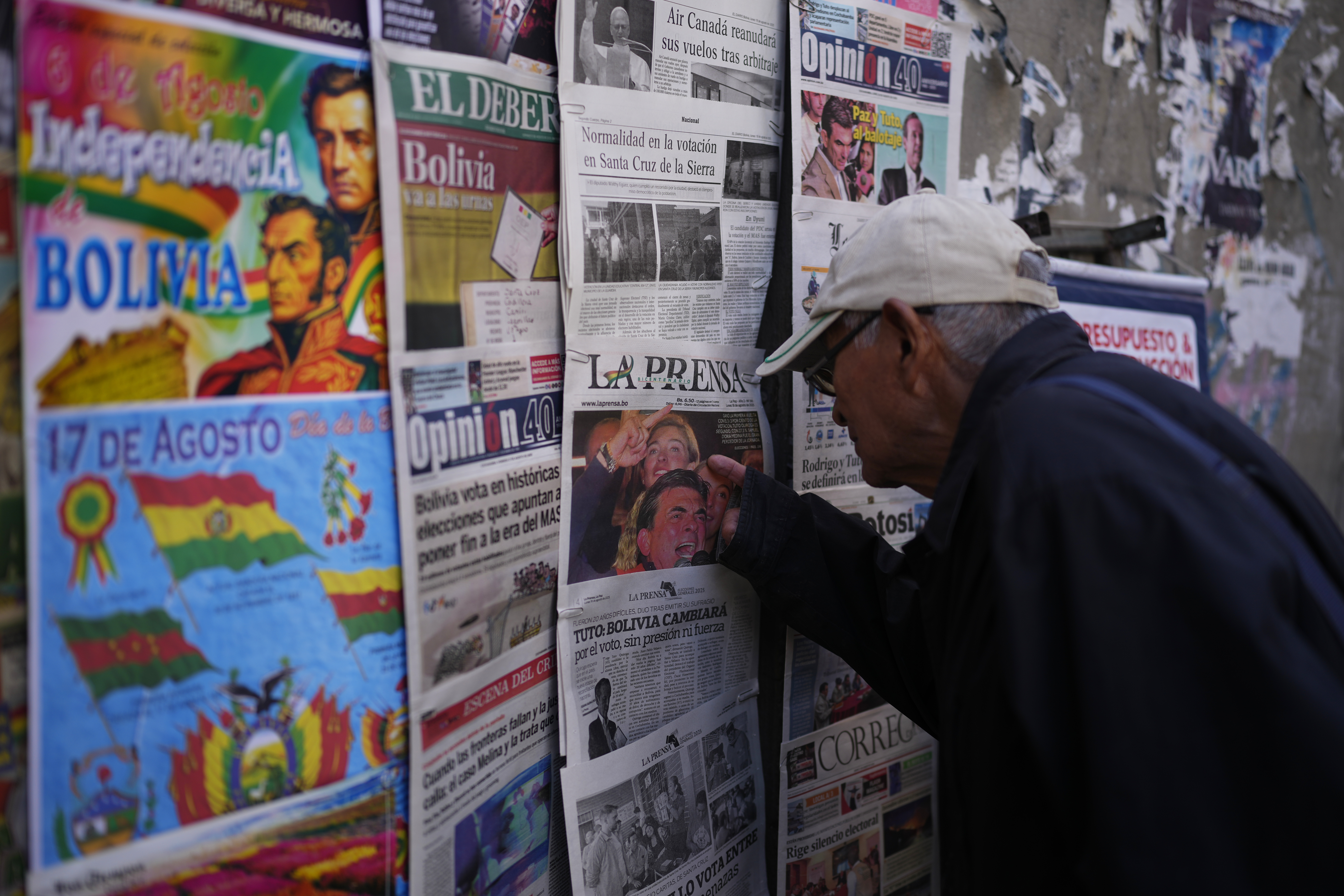 A man looks at newspapers with election results pinned to the wall