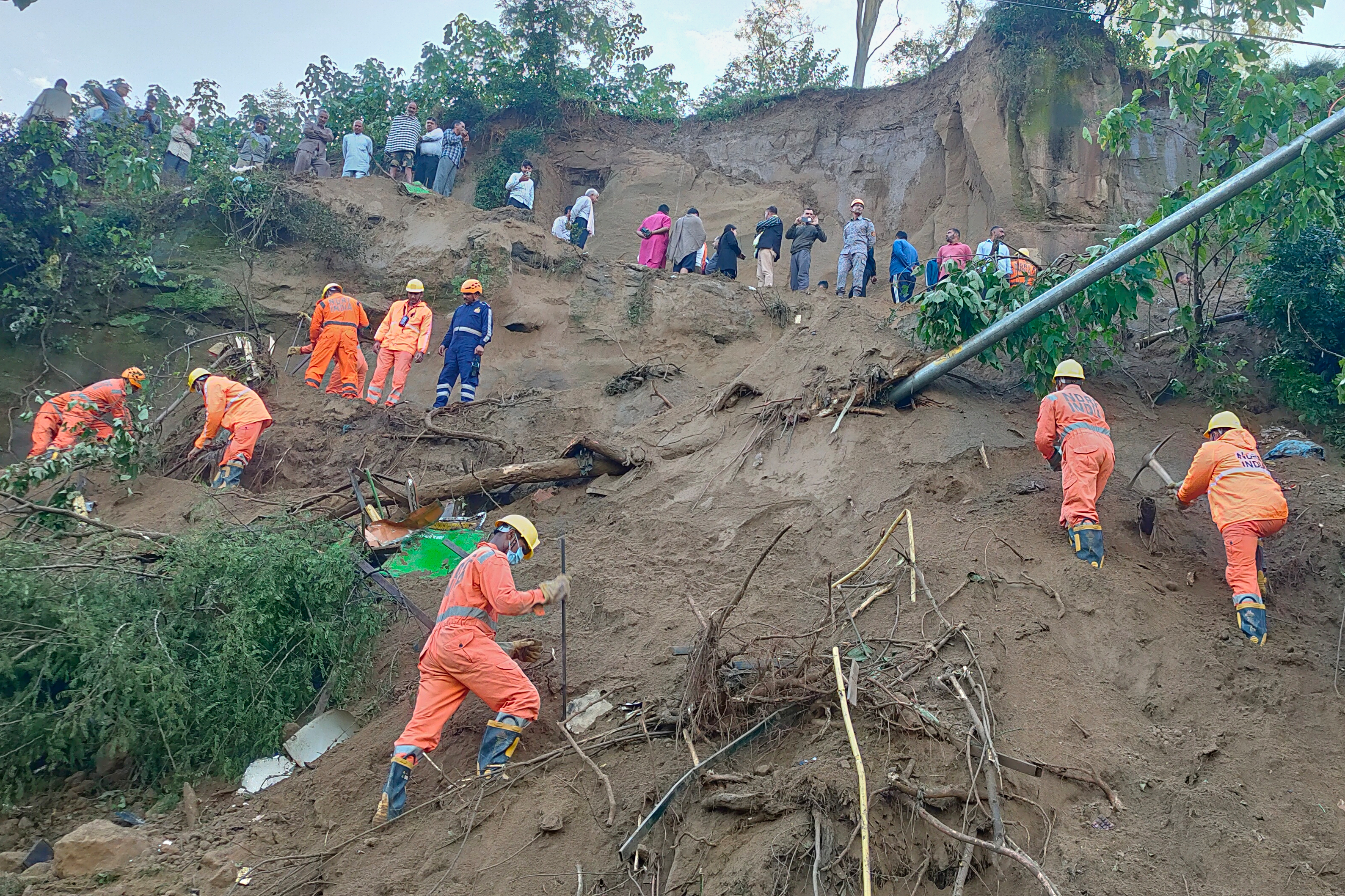 In this handout photo released by the National Disaster Response Force (NDRF), NDRF personnel look for survivors after debris from a massive landslide hit a passenger bus Tuesday night, near Bilaspur in India's northern state of Himachal Pradesh, Wednesday, Oct. 8, 2025. (NDRF via AP)