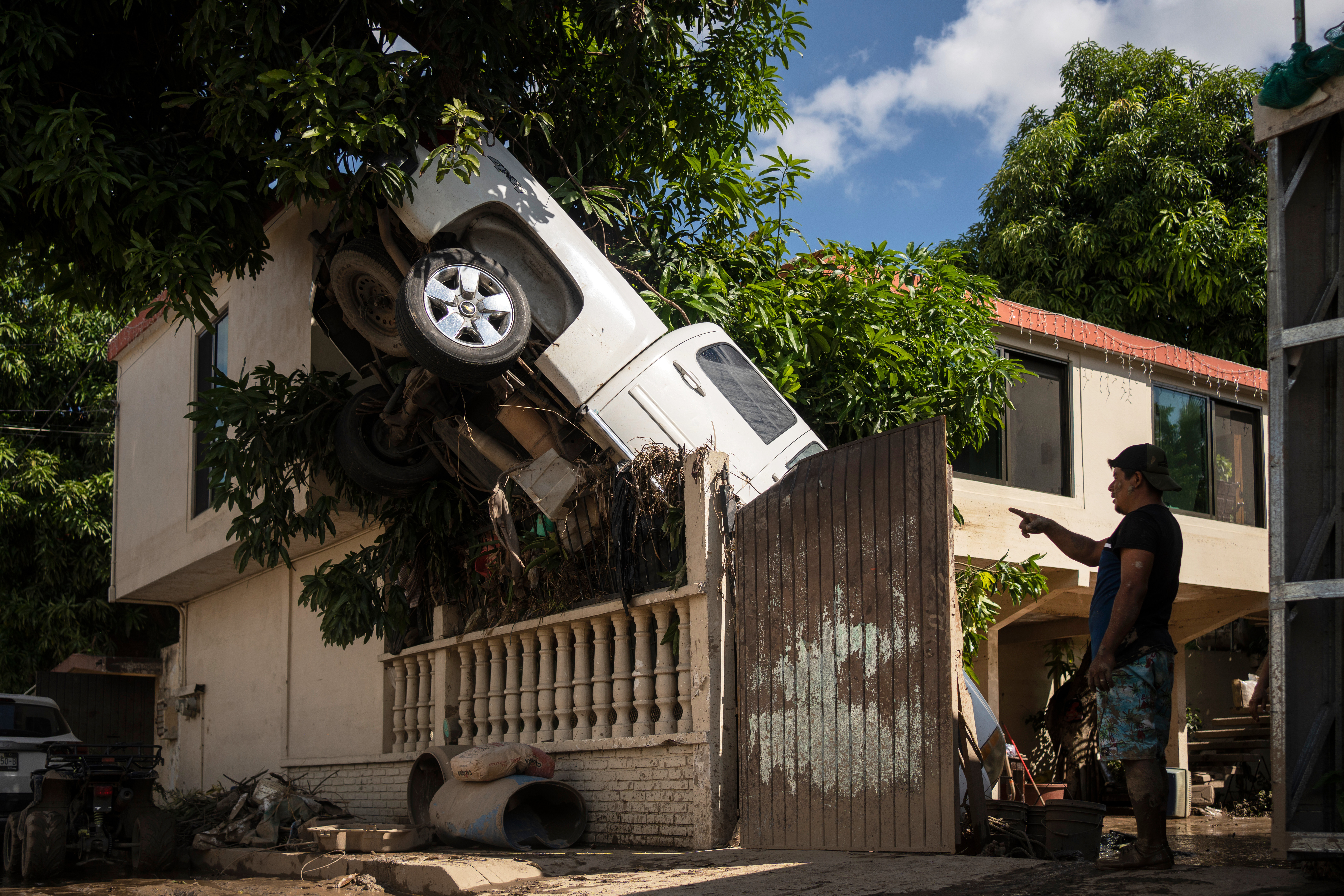 A pick-up truck hangs over a fence.