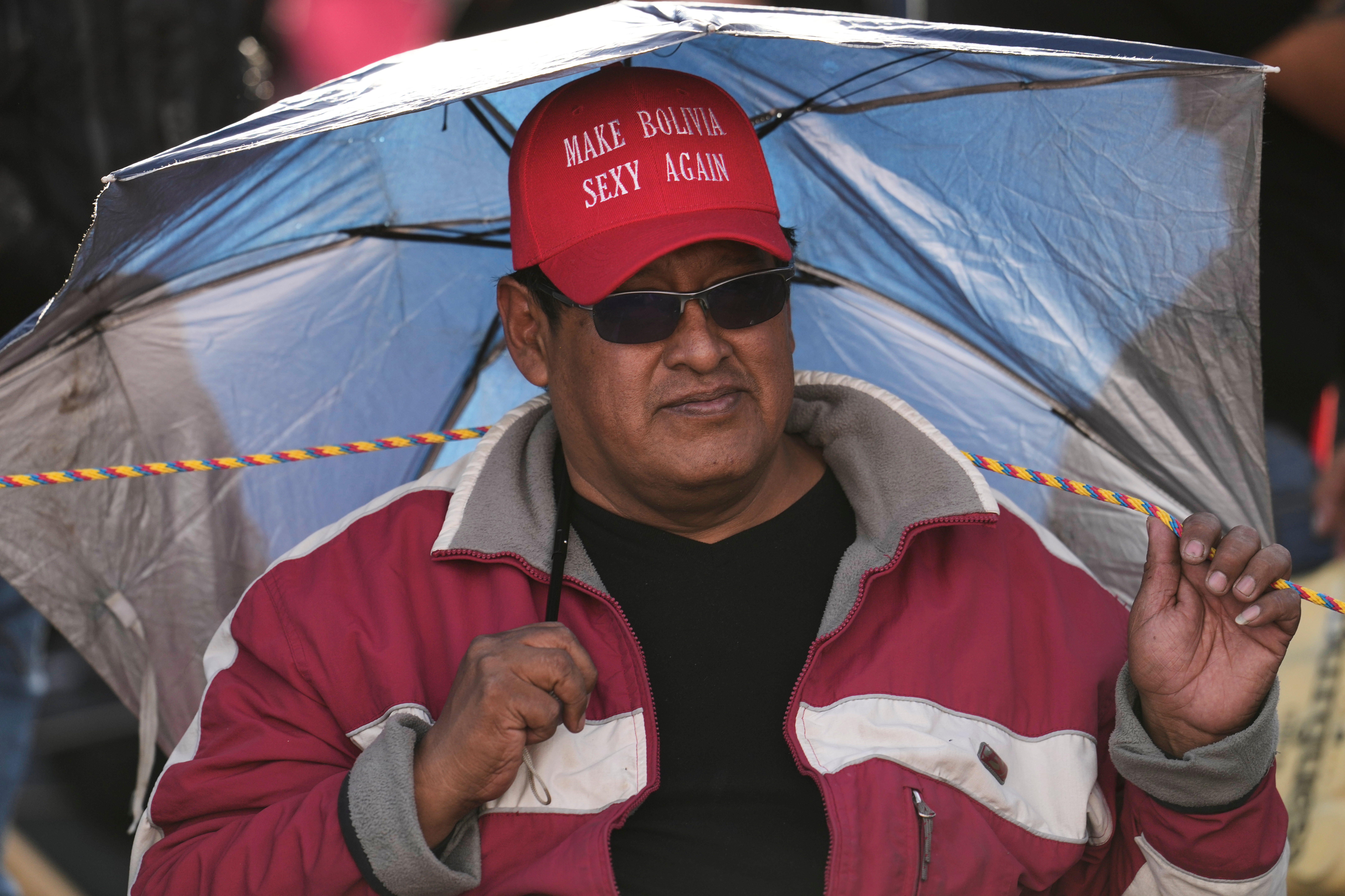 A man standing under an umbrella wears a