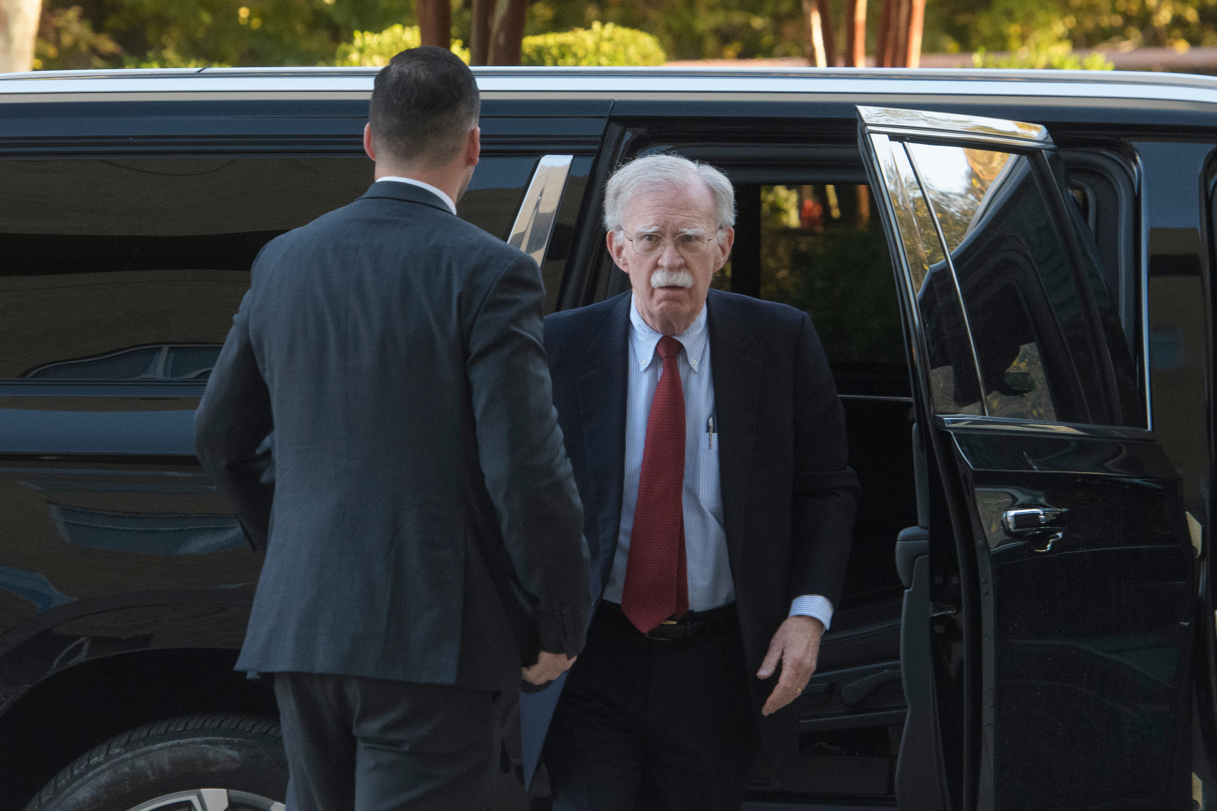 John Bolton exits a black vehicle on his way to court.