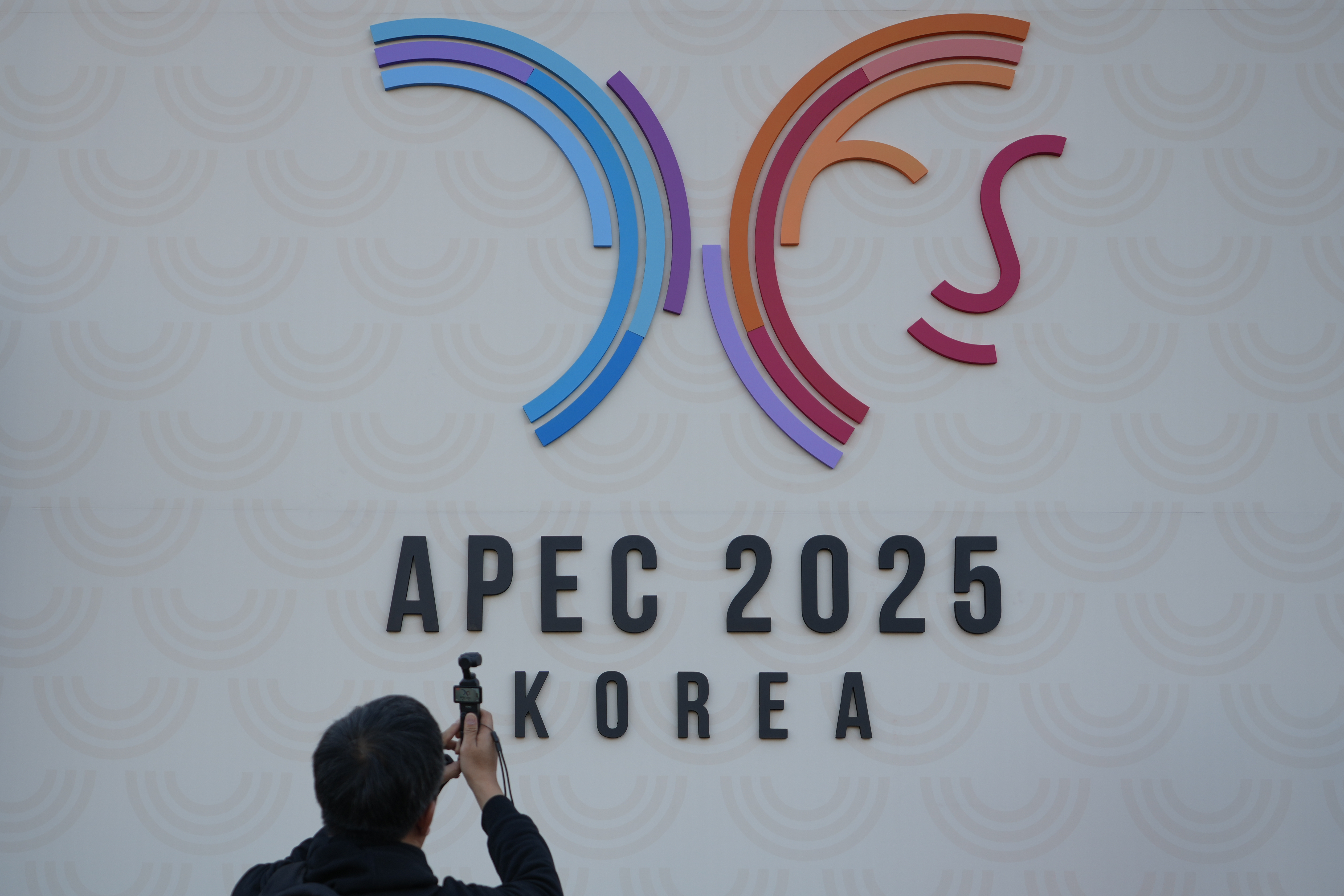 A man films the logo of the Asia-Pacific Economic Cooperation summit (APEC) outside of the venue in Gyeongju, South Korea, Tuesday, Oct. 28, 2025. (AP Photo/Lee Jin-man)