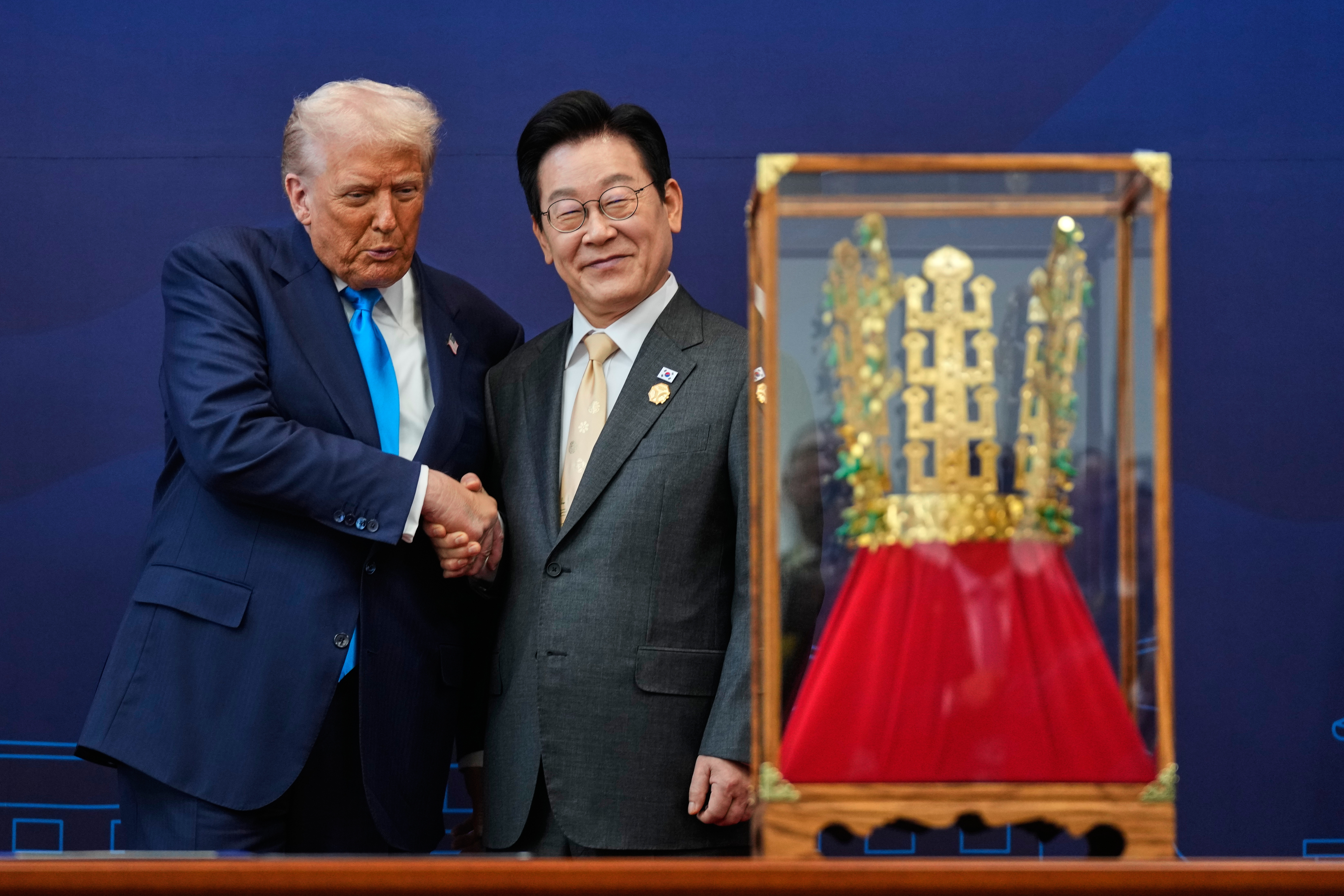 President Donald Trump shakes hands with South Korean President Lee Jae Myung as he receives a gift of a gold crown in Seoul, South Korea