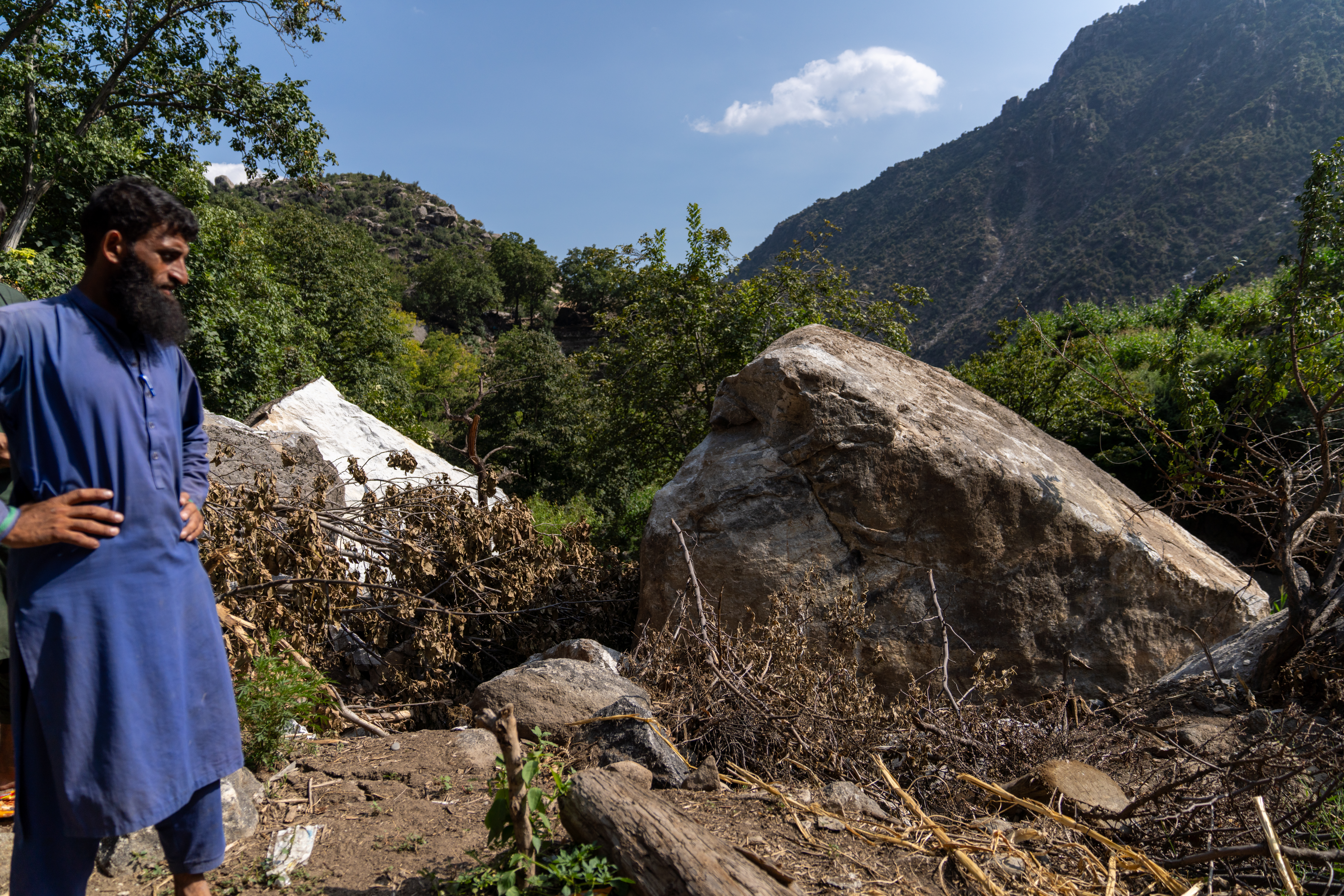 A villager looks at the boulders that destroyed Gulalai's home [Sorin Furcoi/Al Jazeera]