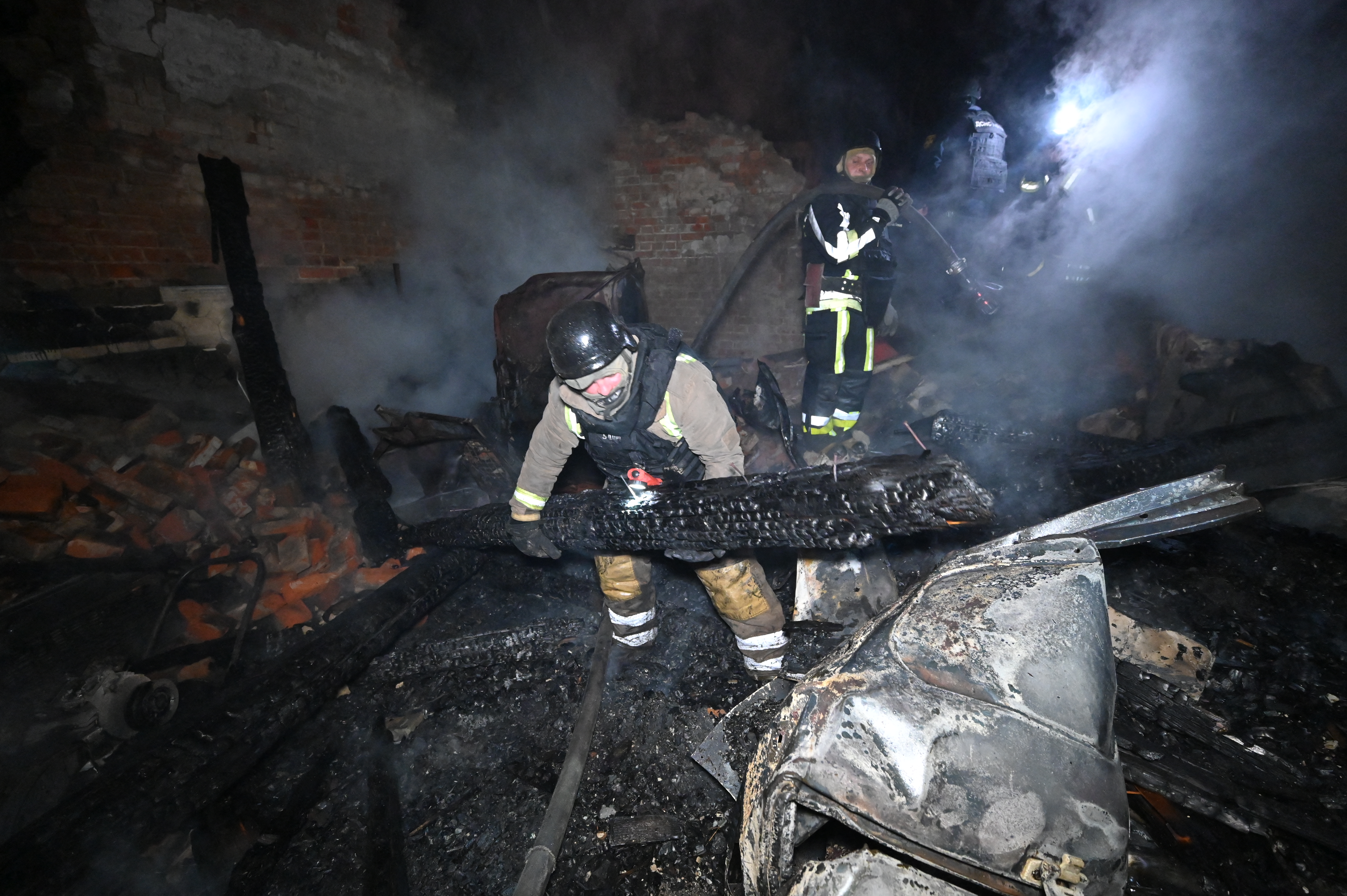 Ukrainian firefighters extinguish a smouldering building following Russian strikes in Kharkiv