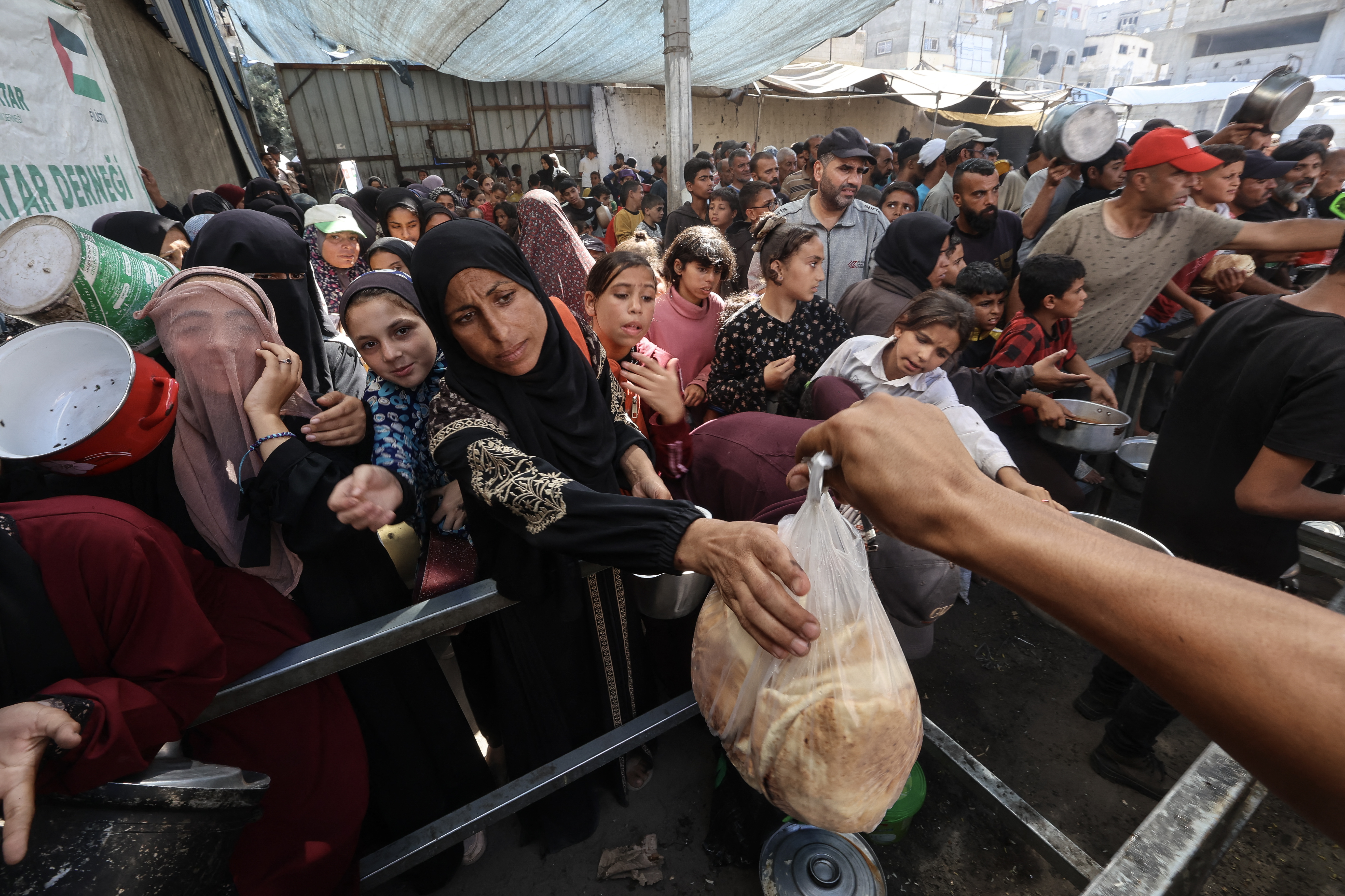 Palestinians gather to receive food portions from a charity kitchen.