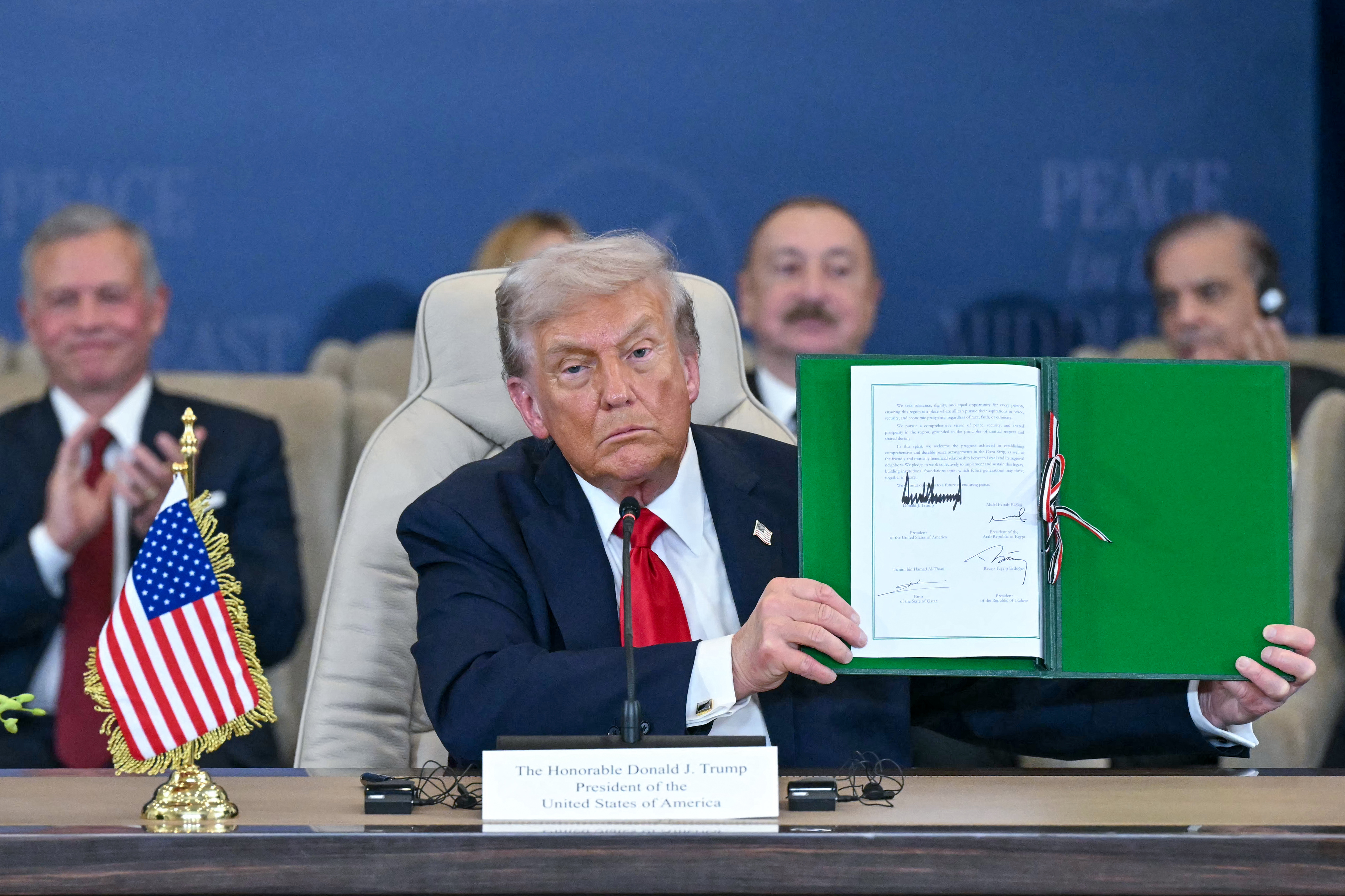 US President Donald Trump shows a signed document during a summit on Gaza in Sharm el-Sheikh on October 13, 2025.