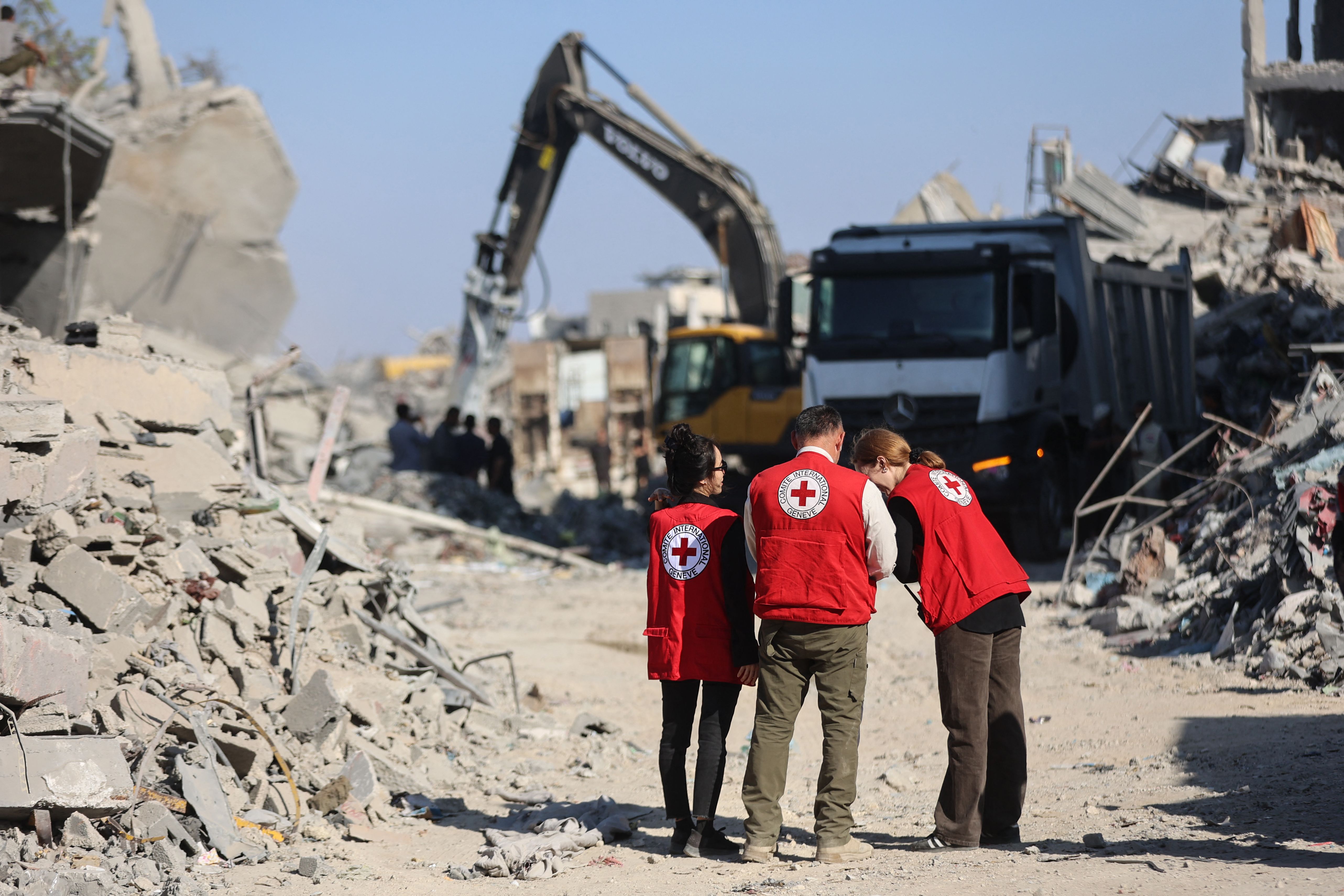 Members of the Red Cross stand amid the rubble of destroyed buildings as heavy machinery operates in the al-Tuffah neighbourhood of Gaza City on October 27, 2025.
