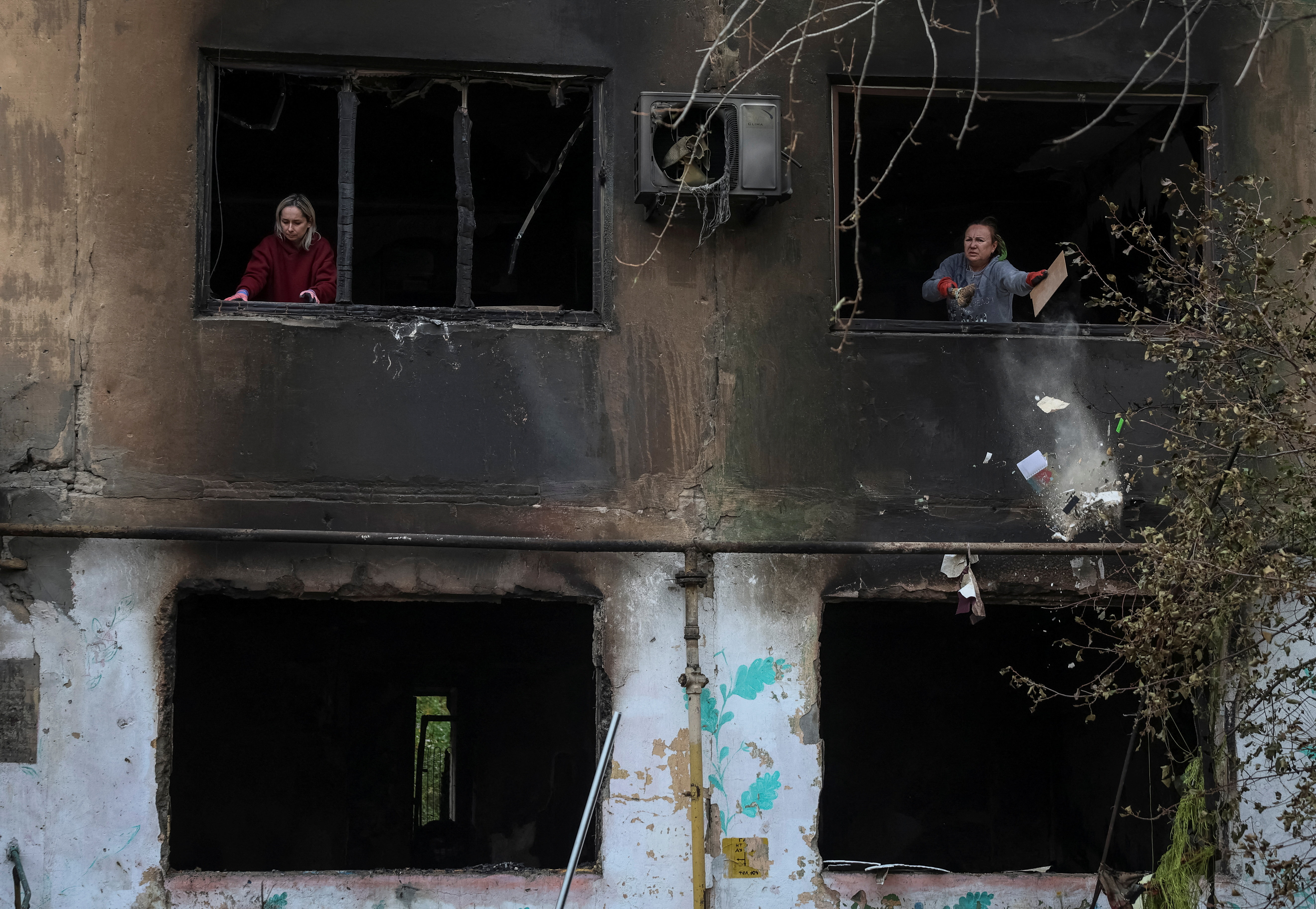 Residents remove broken glass from windows of an apartment building damaged by a Russian drone strike, amid Russia's attack on Ukraine, in the town of Shakhtarske in Dnipropetrovsk region, Ukraine October 19, 2025. REUTERS/Anatolii Stepanov