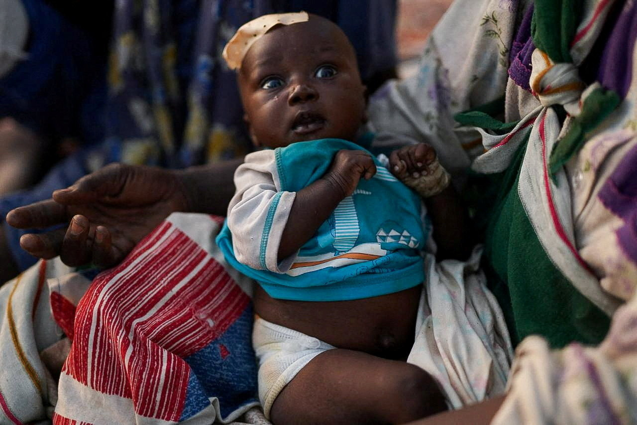 A grandchild of Ikram Abdelhameed looks on while sitting at a camp for displaced people who fled from al-Fashir to Tawila, North Darfur, Sudan, October 27, 2025. REUTERS/Mohammed Jamal