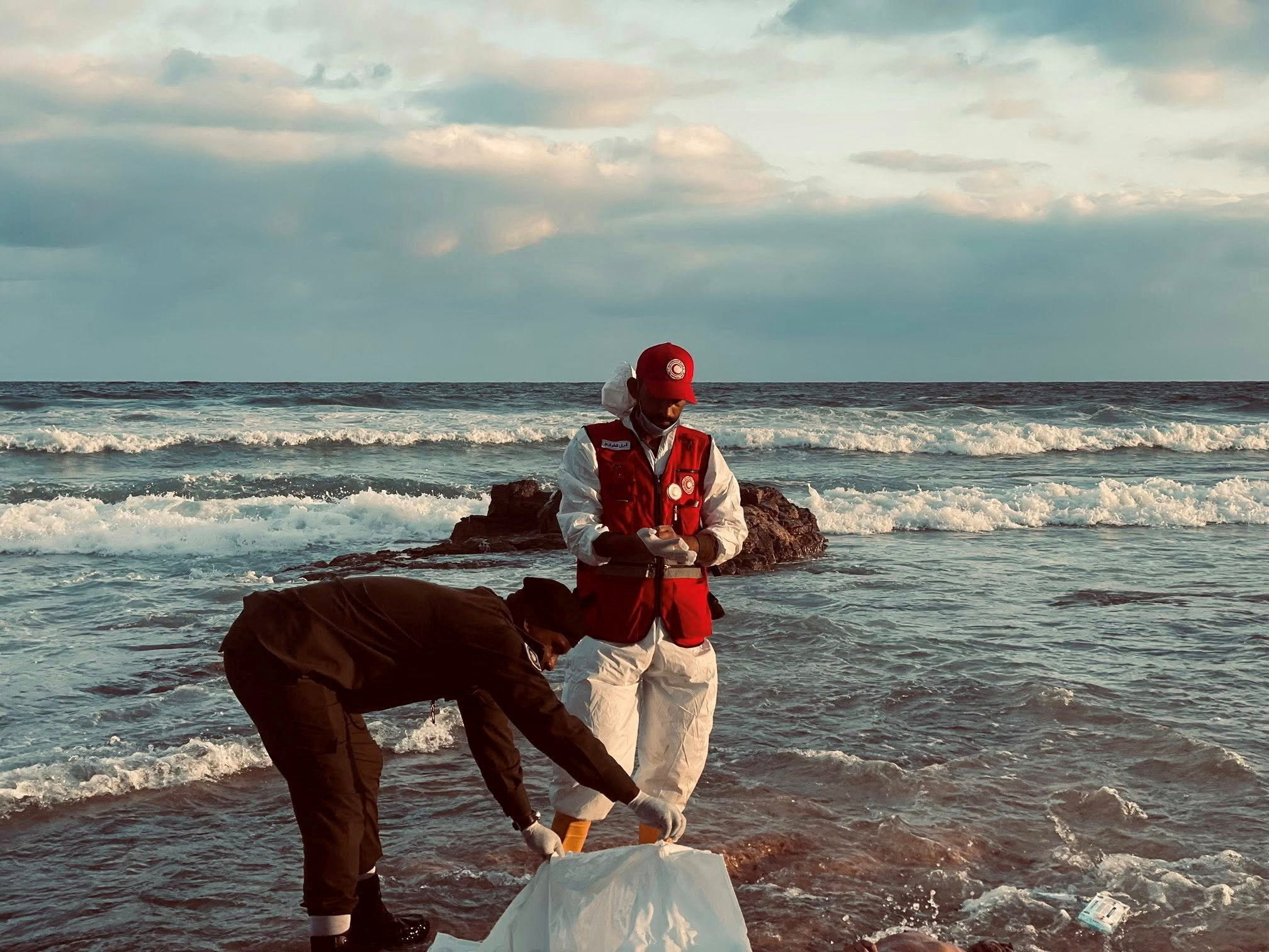 A member of the Red Crescent stands next to a body bag in a location given as near Surman, Libya, after a migrant boat capsized west of Libya's capital Tripoli,