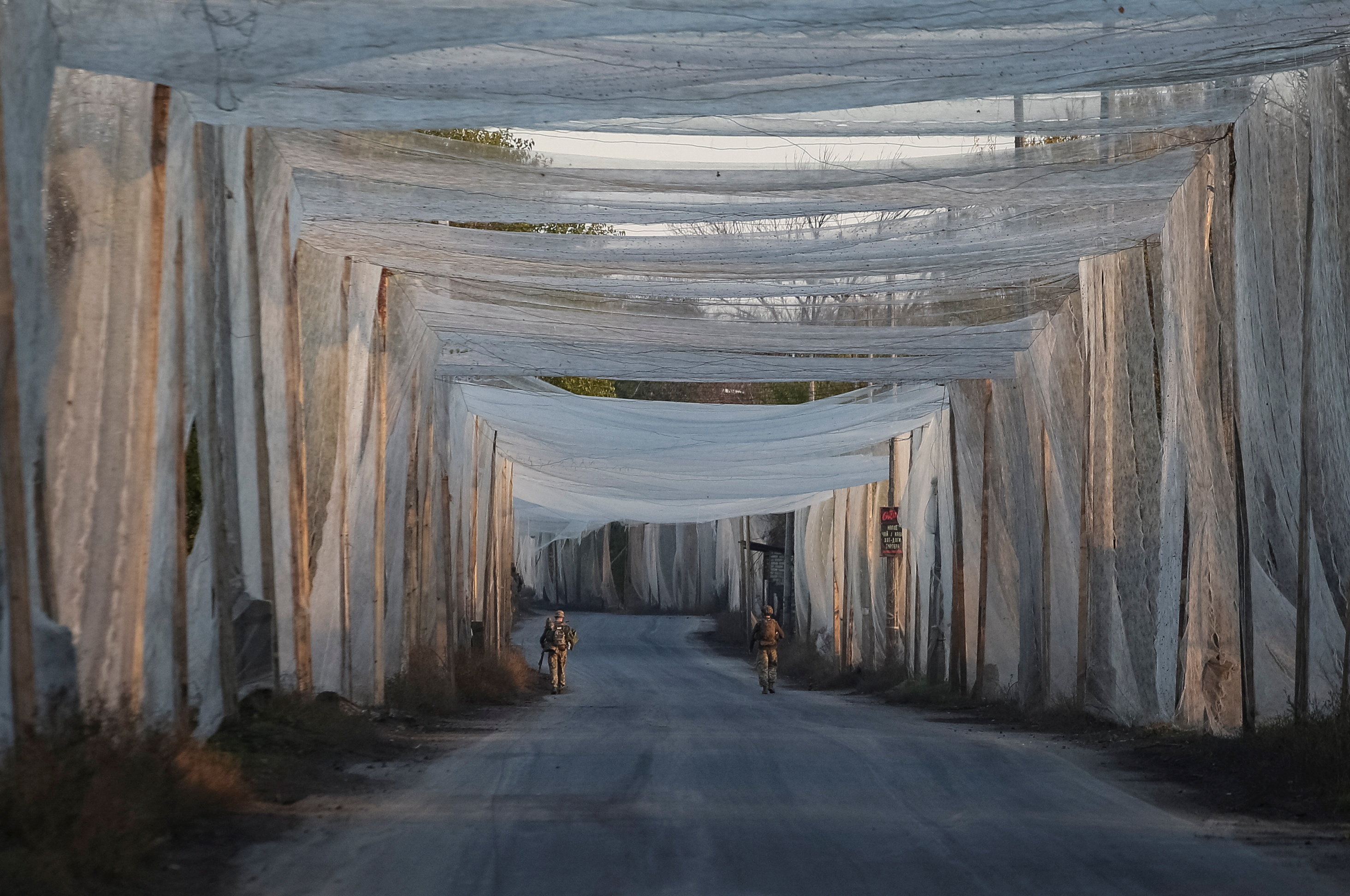 Ukrainian servicemen walk along a road covered with anti-drone nets, amid Russia's attack on Ukraine, in the frontline town of Kostiantynivka in Donetsk region, Ukraine November 3, 2025. REUTERS/Anatolii Stepanov TPX IMAGES OF THE DAY