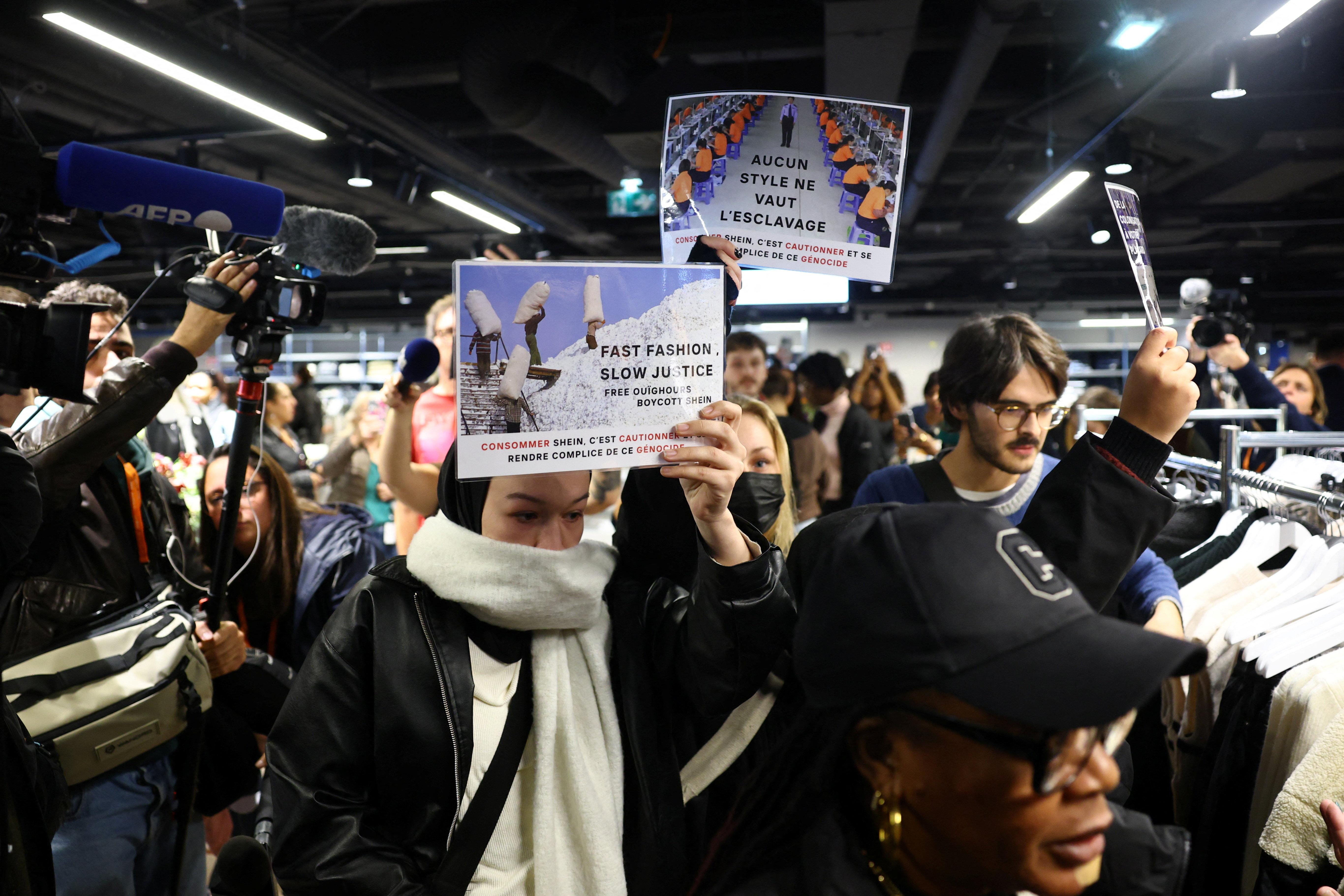Protesters hold placards which reads "Fast fashion, slow justice. Free Uyghurs, boycott Shein. Buying Shein is condoning and becoming complicit in this genocide" during a protest inside the first physical space of November 5, 2025 [Sarah Meyssonnier/Reuters]
