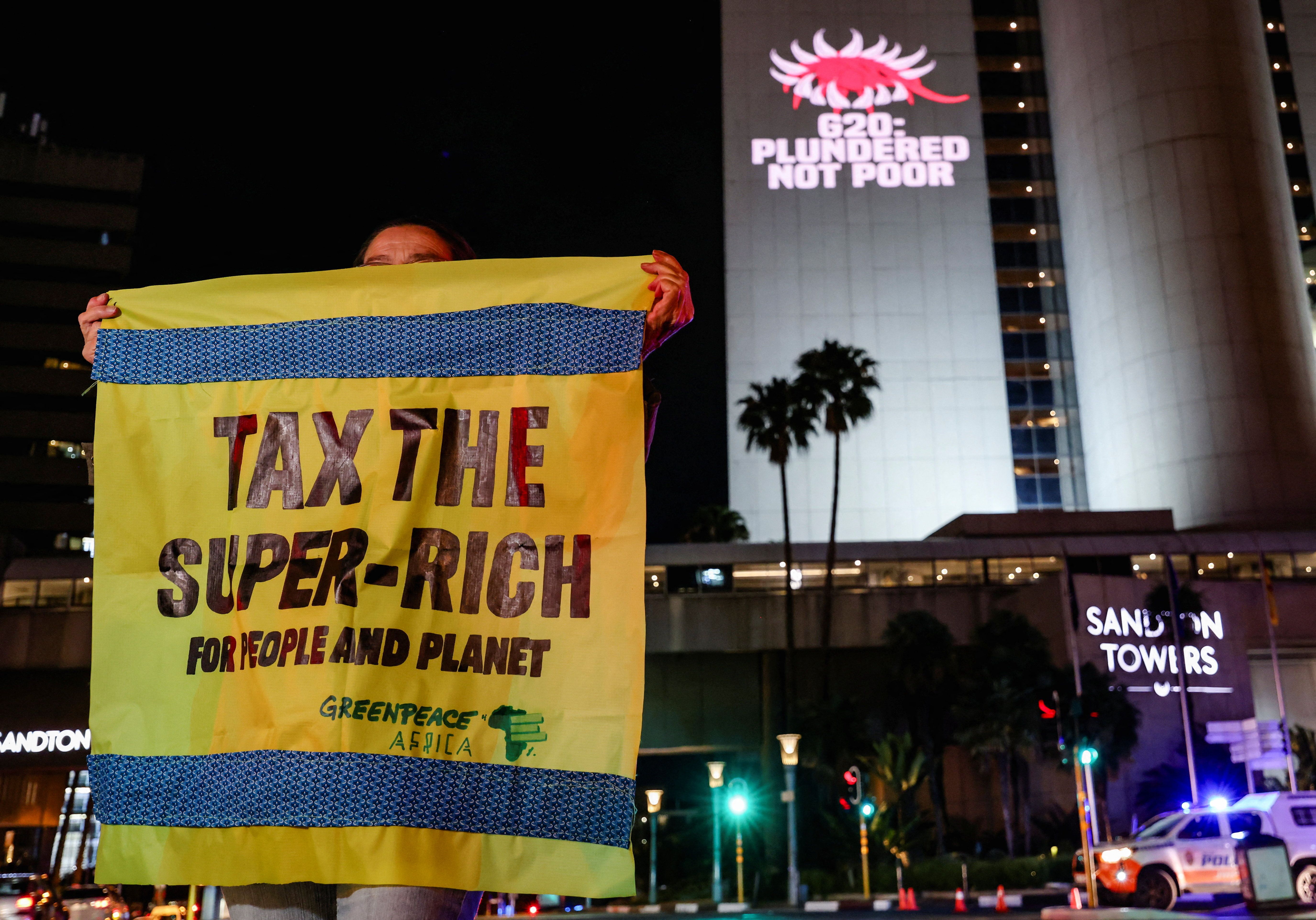 A Greenpeace activist holds a banner as she joins a Glasgow Actions Team projection calling for bold debt reform, stronger climate action and urgent responses to the global development crisis as leaders prepare for the first G20 summit hosted in Africa, in Johannesburg, South Africa, November 19, 2025.