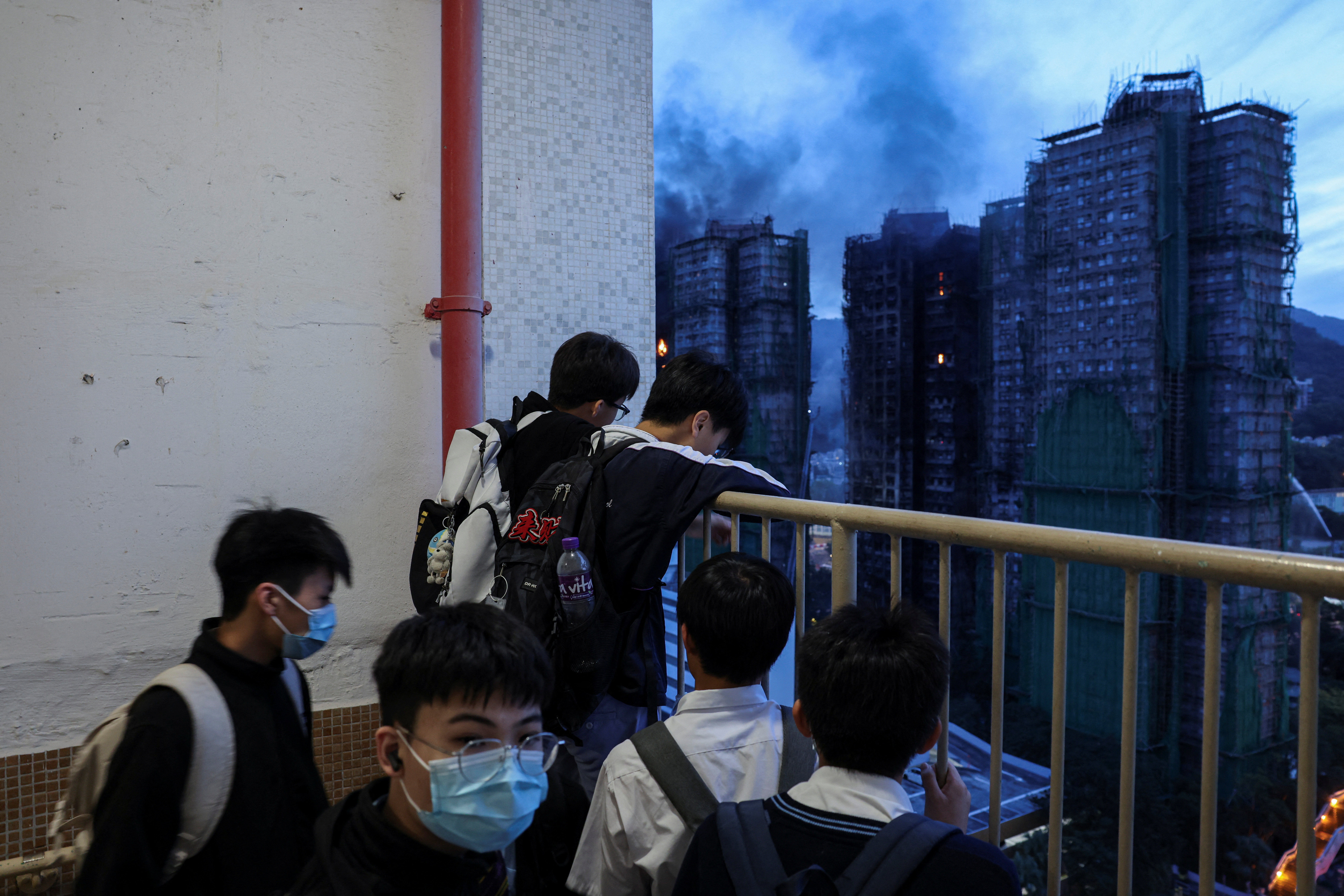 Secondary school students watch the aftermath of the major fire at Wang Fuk Court housing estate, in Tai Po, Hong Kong, China, November 27, 2025. REUTERS/Tyrone Siu
