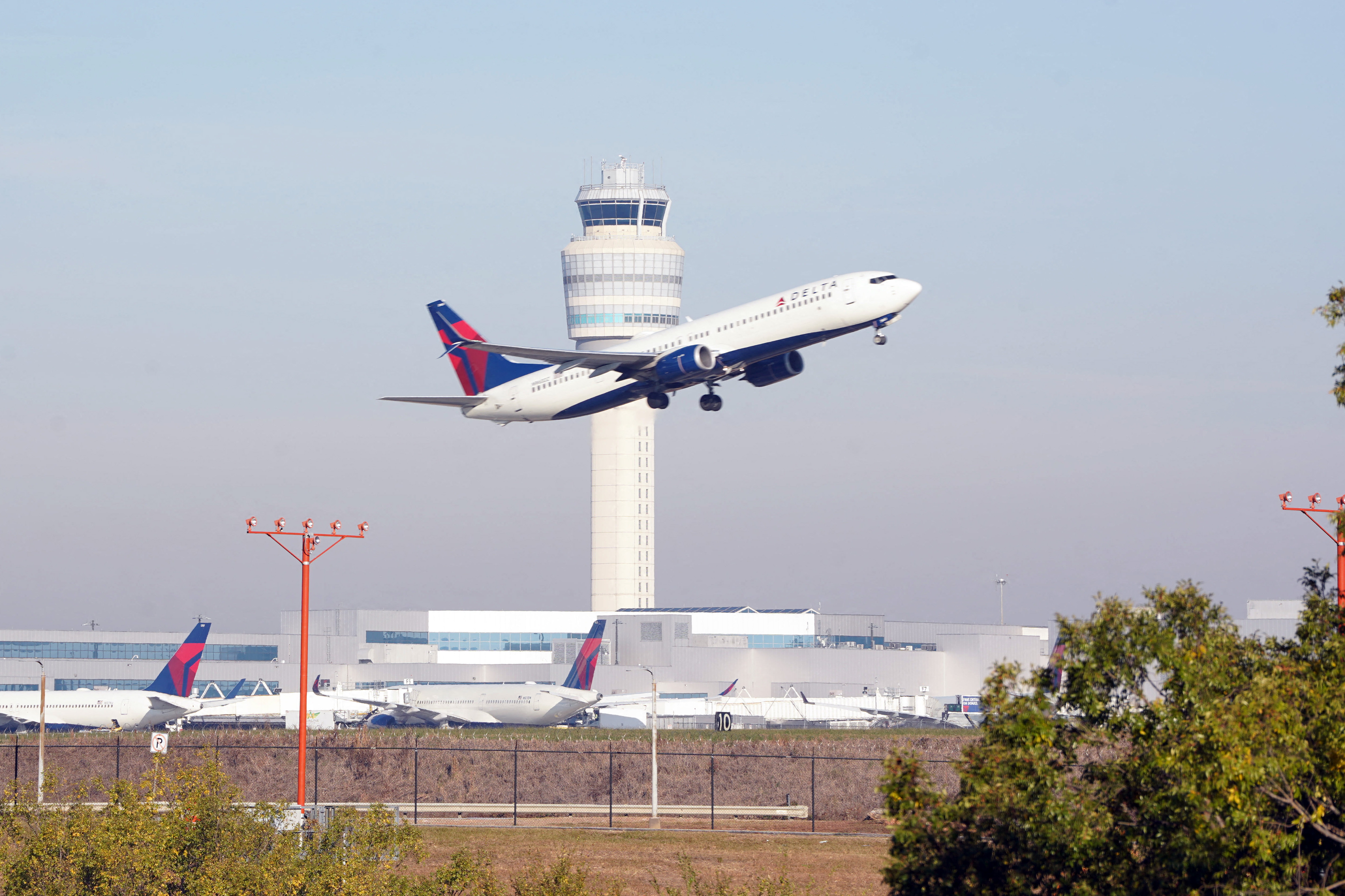 A plane flies past the air traffic control tower as people travel through Hartsfield-Jackson Atlanta International Airport in the US