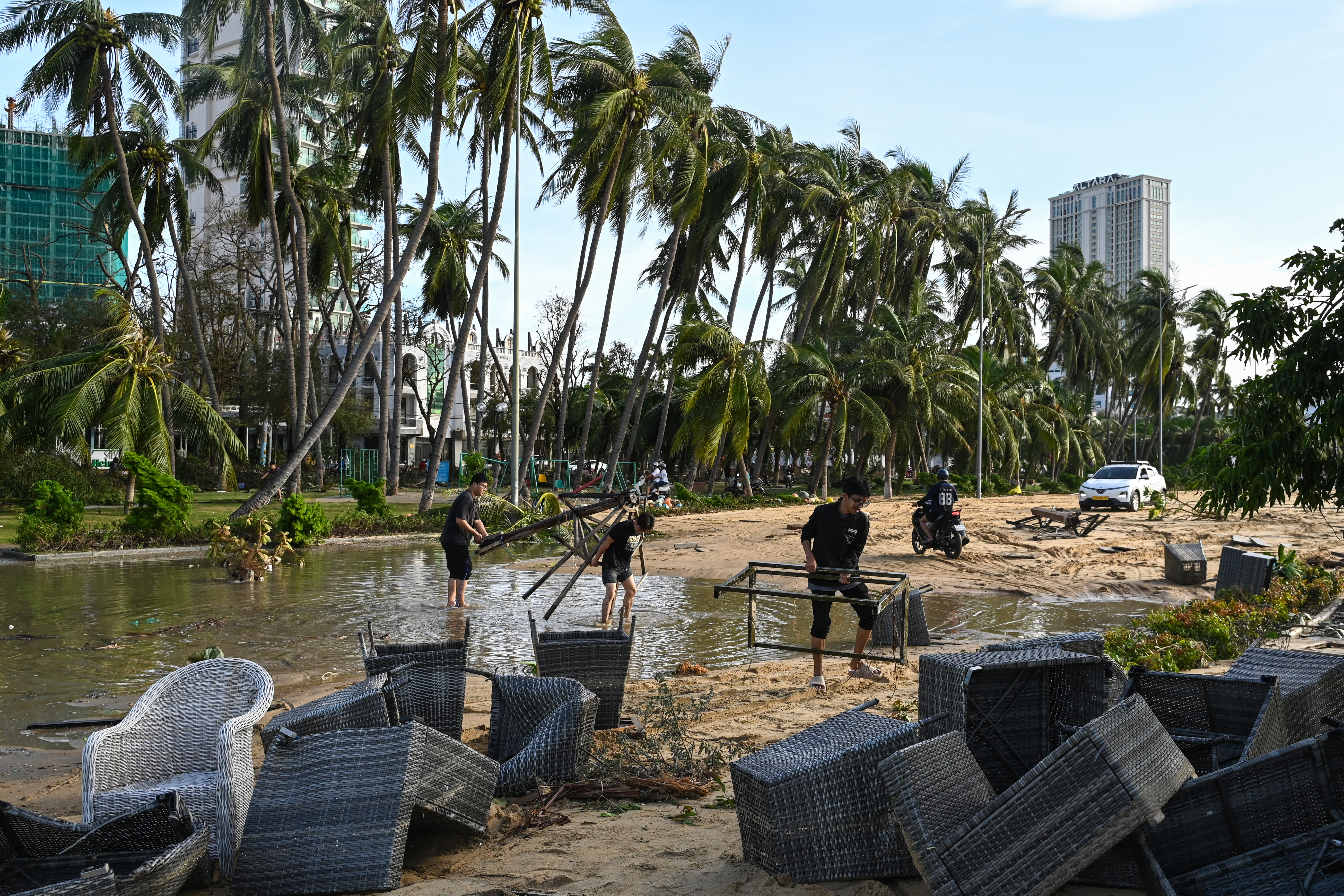 People clear debris in a coastal area.
