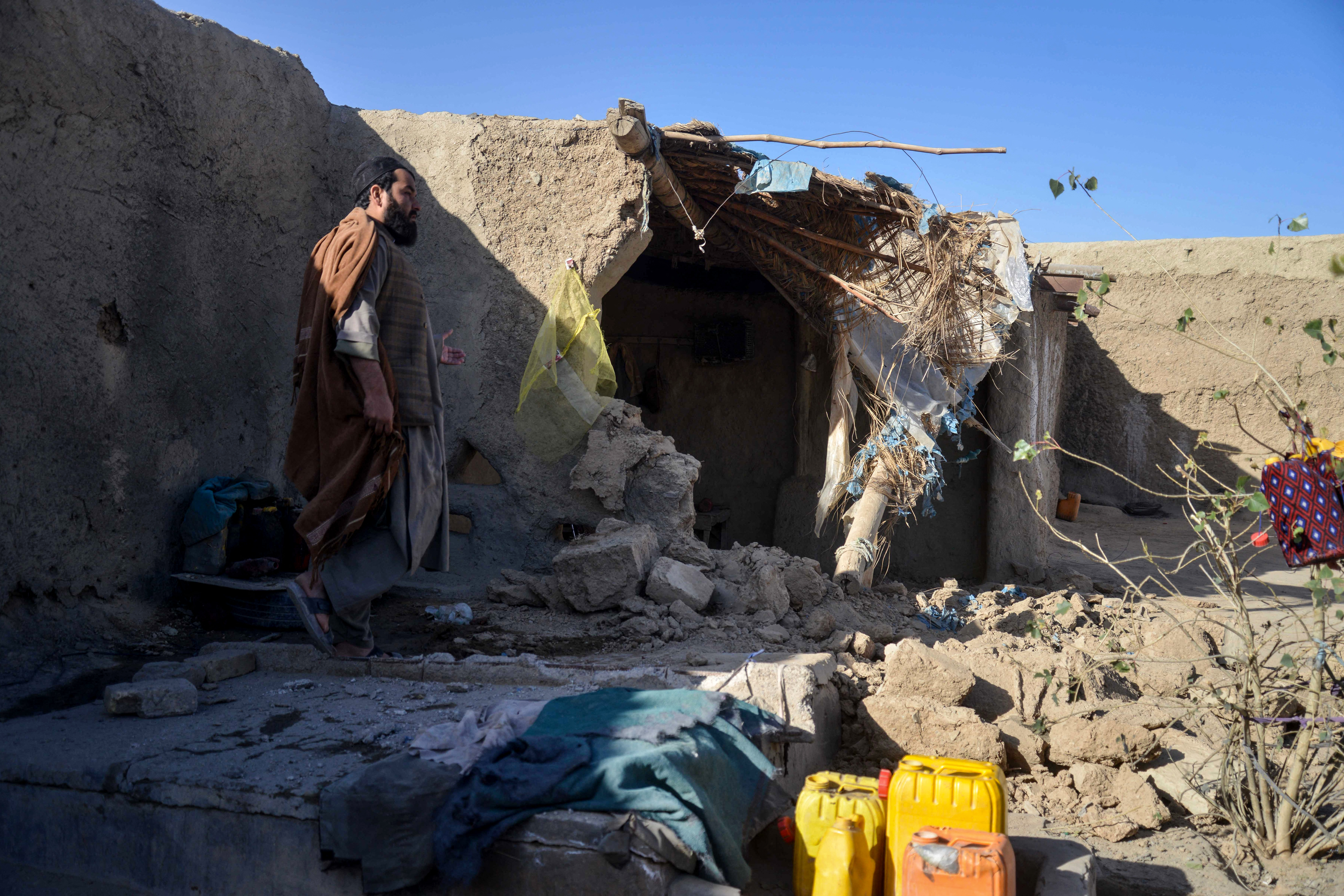 An Afghan man inspects a damaged house.