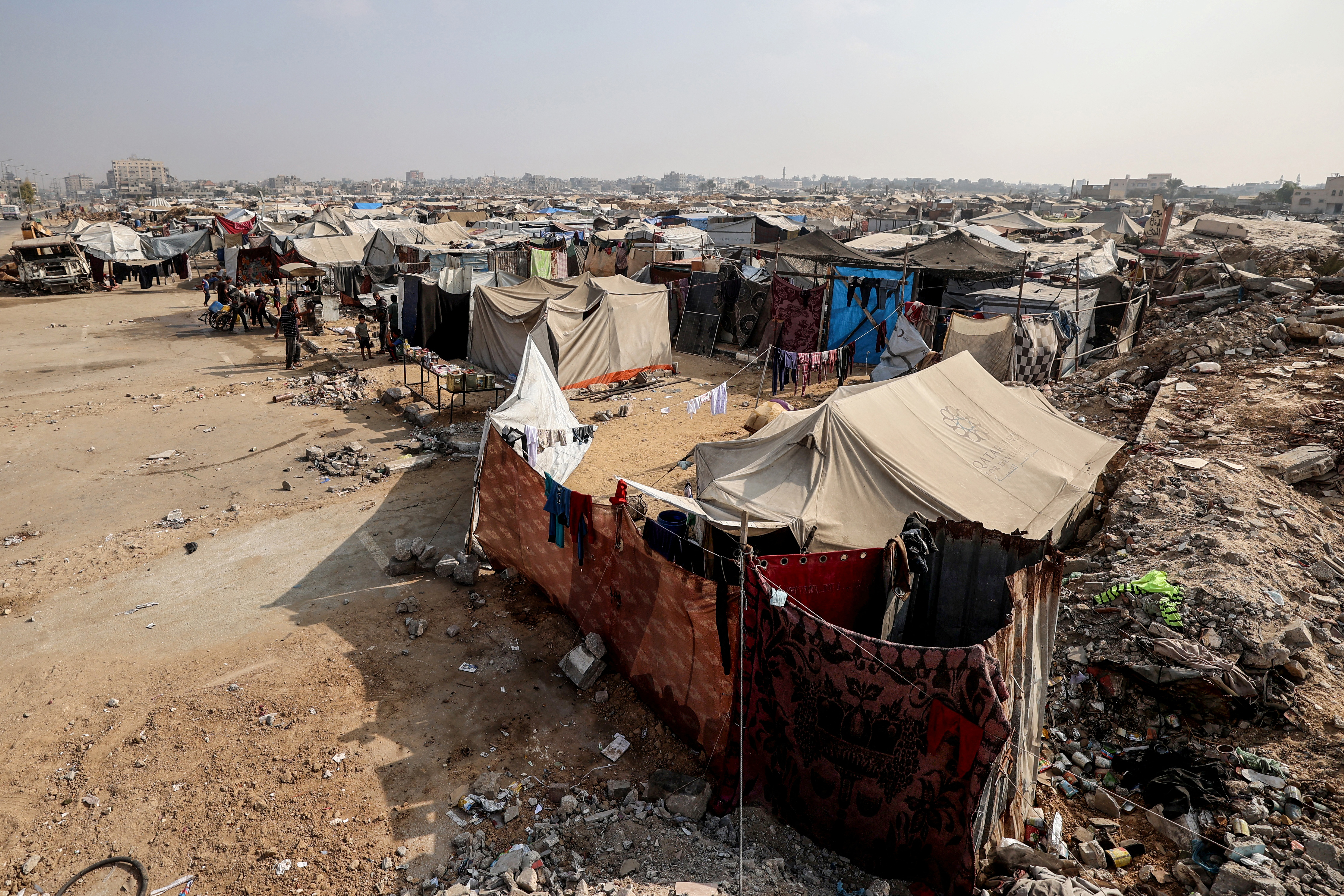 Makeshift shelters are erected along the road amid mud and rubble.