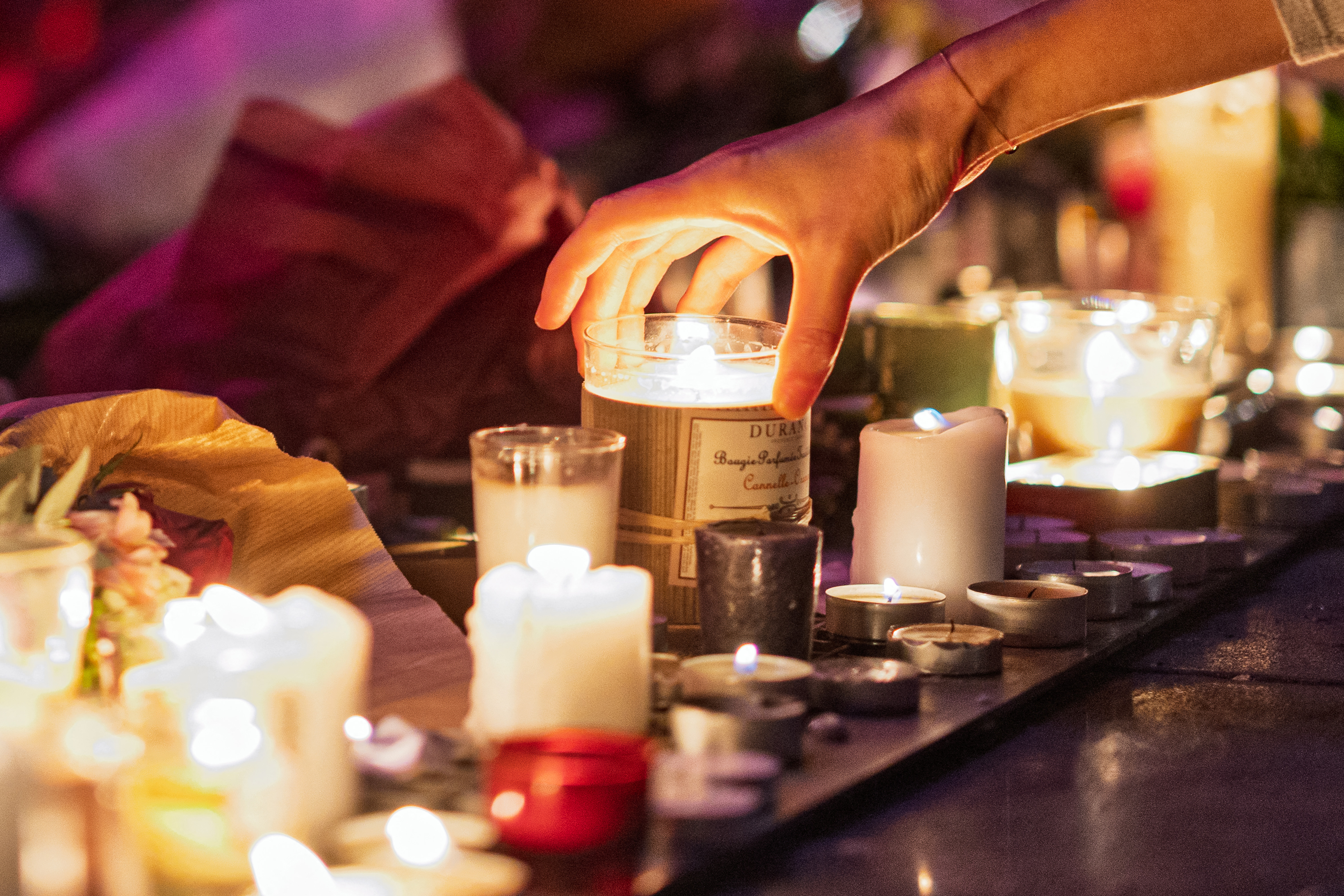 People lay flowers and light candles in tribute to the 130 civilians killed in the November 13, 2015 Paris terror attacks at a temporary memorial at Place de la Republique, in Paris, on November 12, 2025. [Joel Saget/AFP]