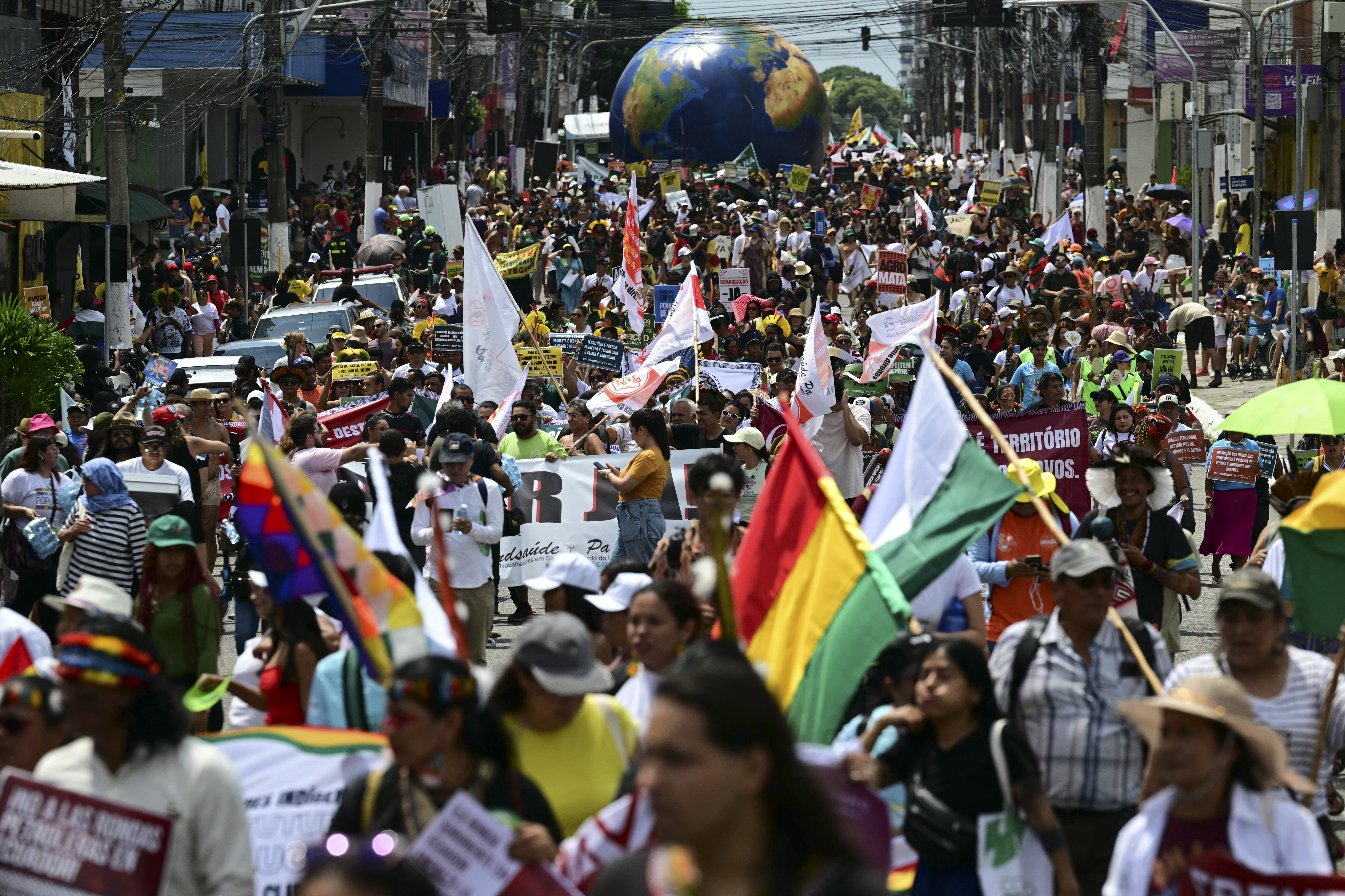 Thousands of people take part in a protest march, waving flags.