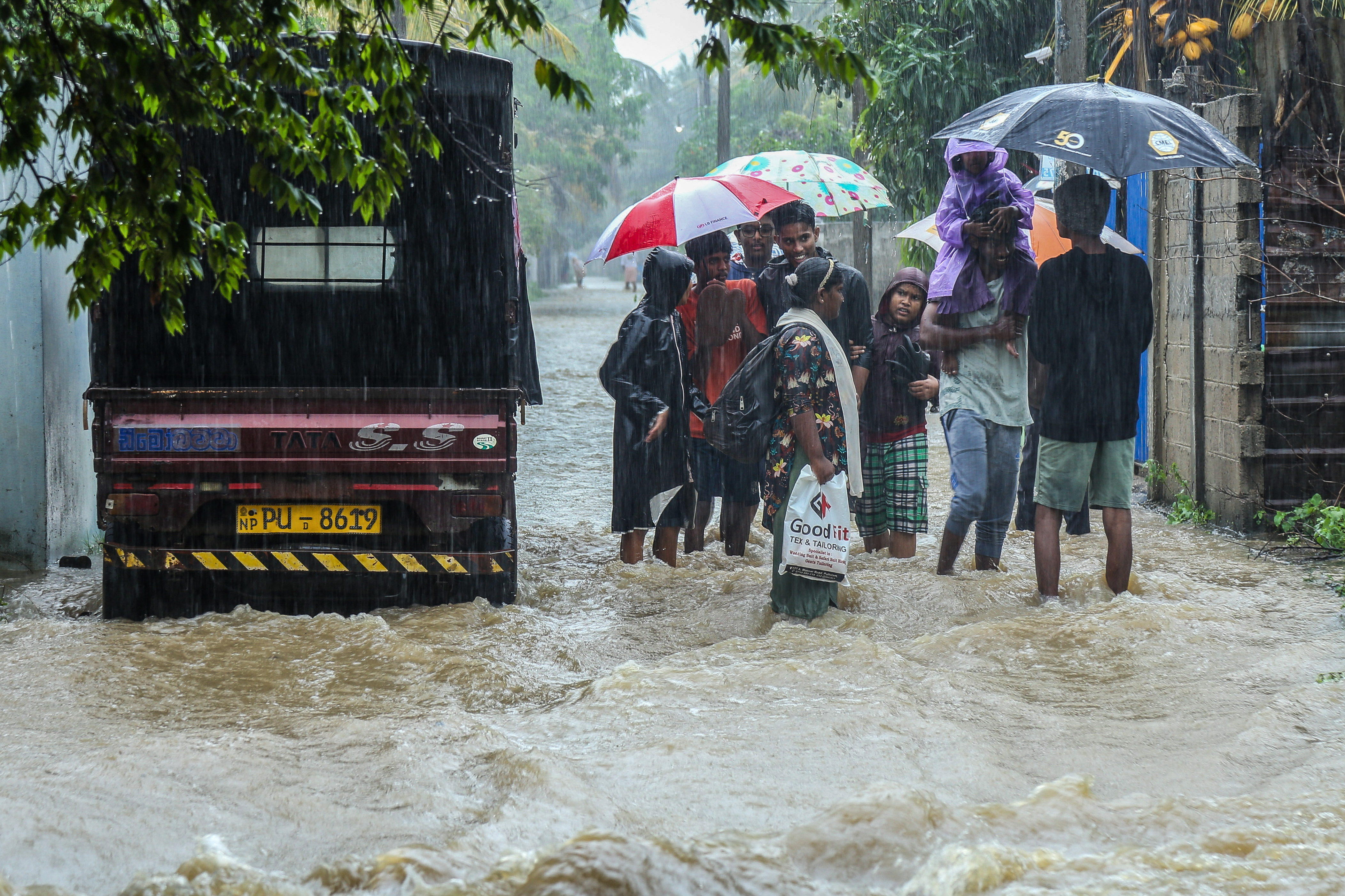 Residents wade through a flooded street during heavy rainfall in Puttalam on November 27, 2025. Floods and landslides triggered by heavy rain killed at least 40 people and injured 10 across Sri Lanka this week, with 21 others missing, authorities said on November 27