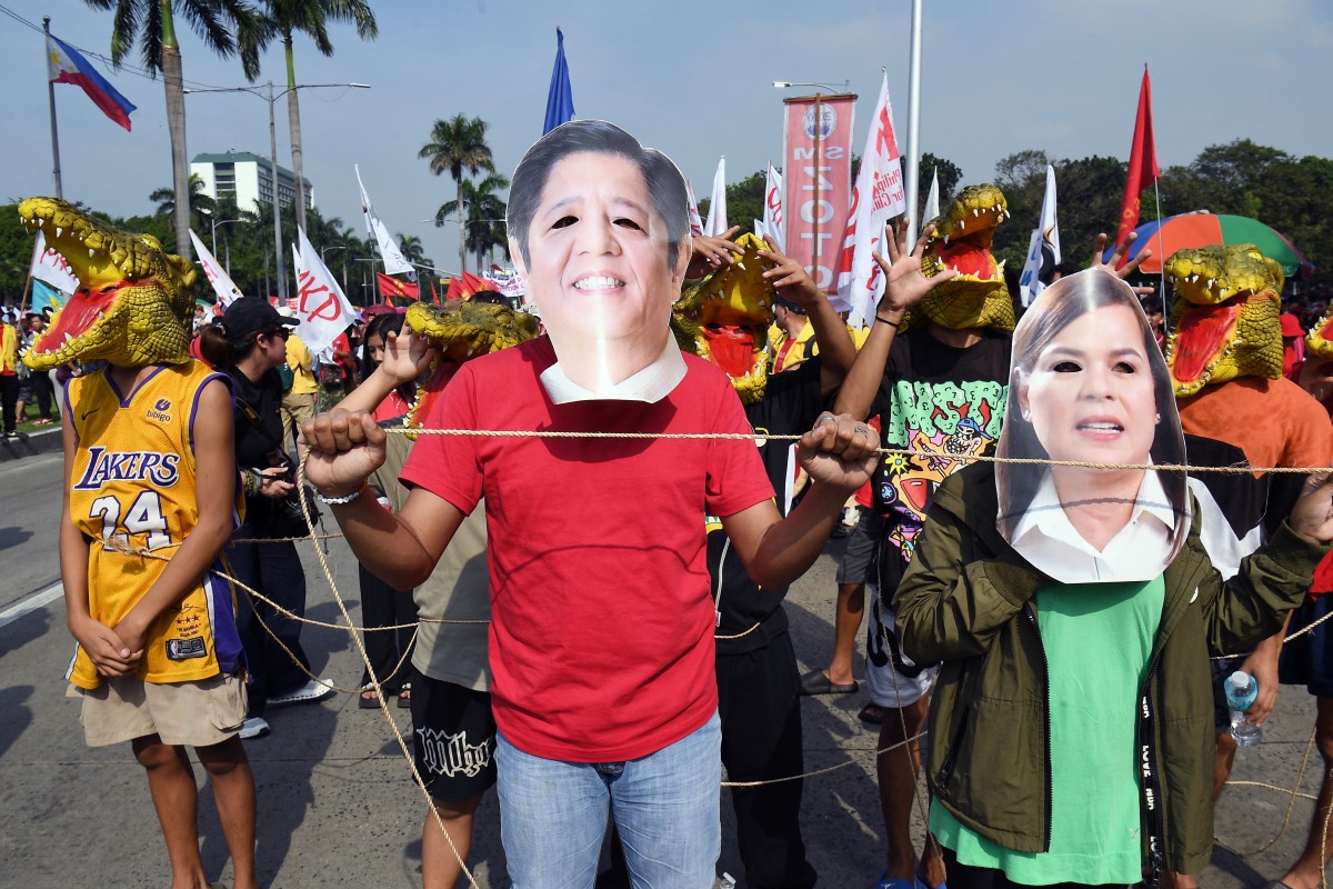Protesters wearing face masks depicting Philippine President Ferdinand Marcos (C) and Vice President Sara Duterte (R) take part in a rally.