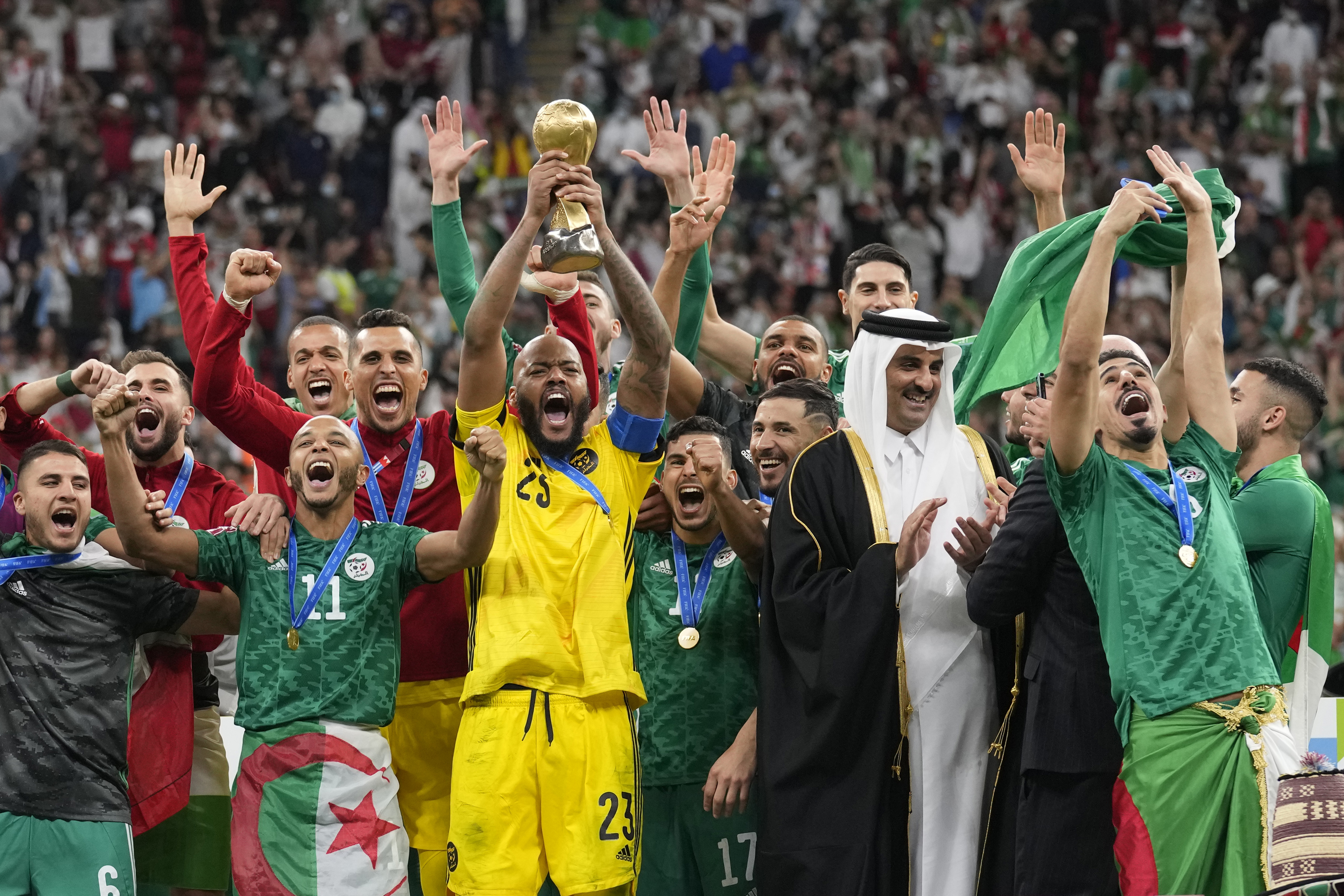 Algeria goalkeeper Rais Mbolhi holds up the winner trophy after received it from Qatar's Emir Sheikh Tamim bin Hamad Al Thani, second right, and FIFA President Gianni Infantino end of the Arab Cup final soccer match between Tunisia and Algeria at the Al Bayt stadium in Al Khor, Qatar, Saturday, Dec. 18, 2021. Algeria won 2-0. (AP Photo/Darko Bandic)