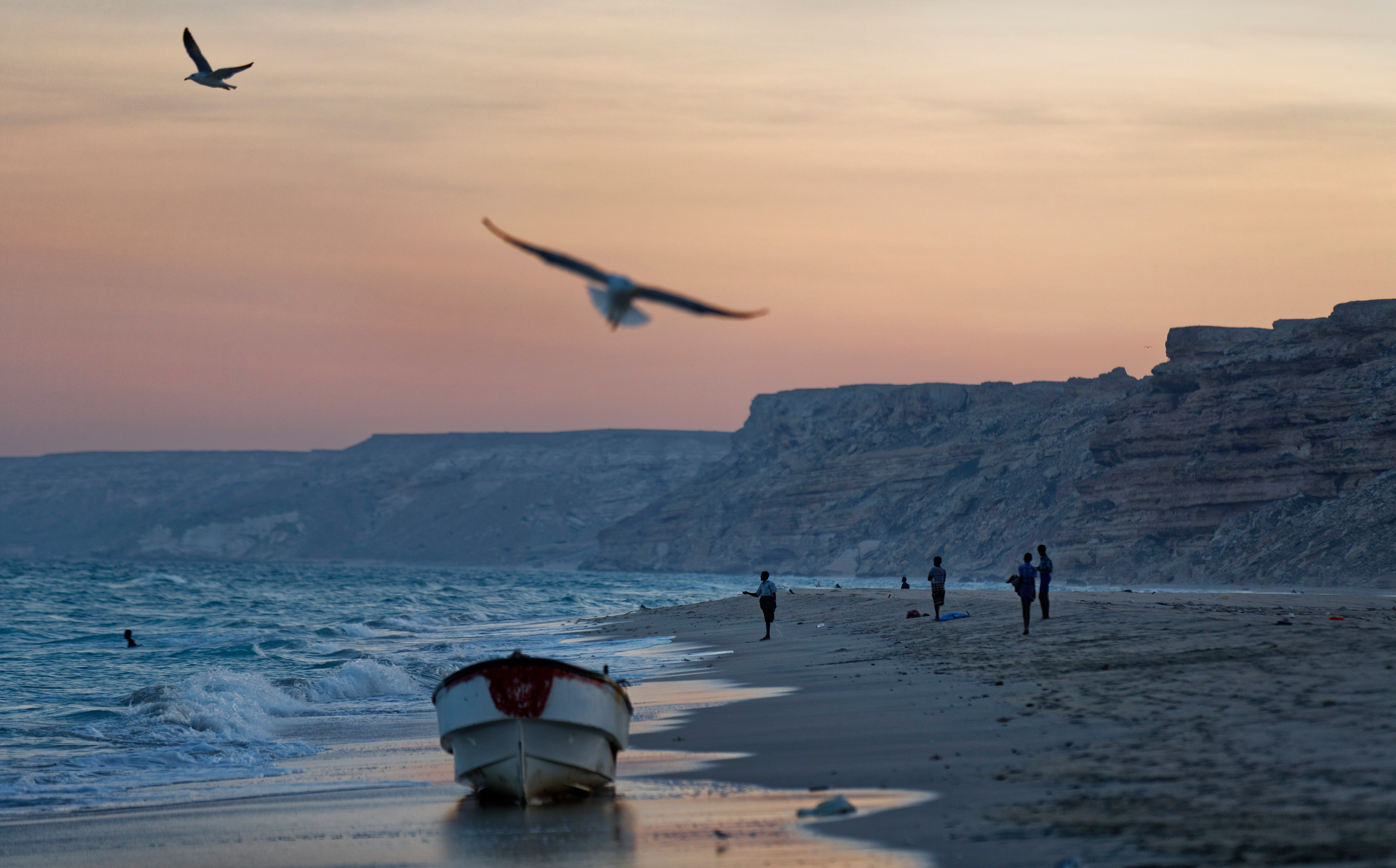 FILE - Fishermen stand on the Indian Ocean beach at dusk in the former pirate village of Eyl, in Somalia's semiautonomous northeastern state of Puntland, Somalia, Monday March 6, 2017. (AP Photo/Ben Curtis, File)