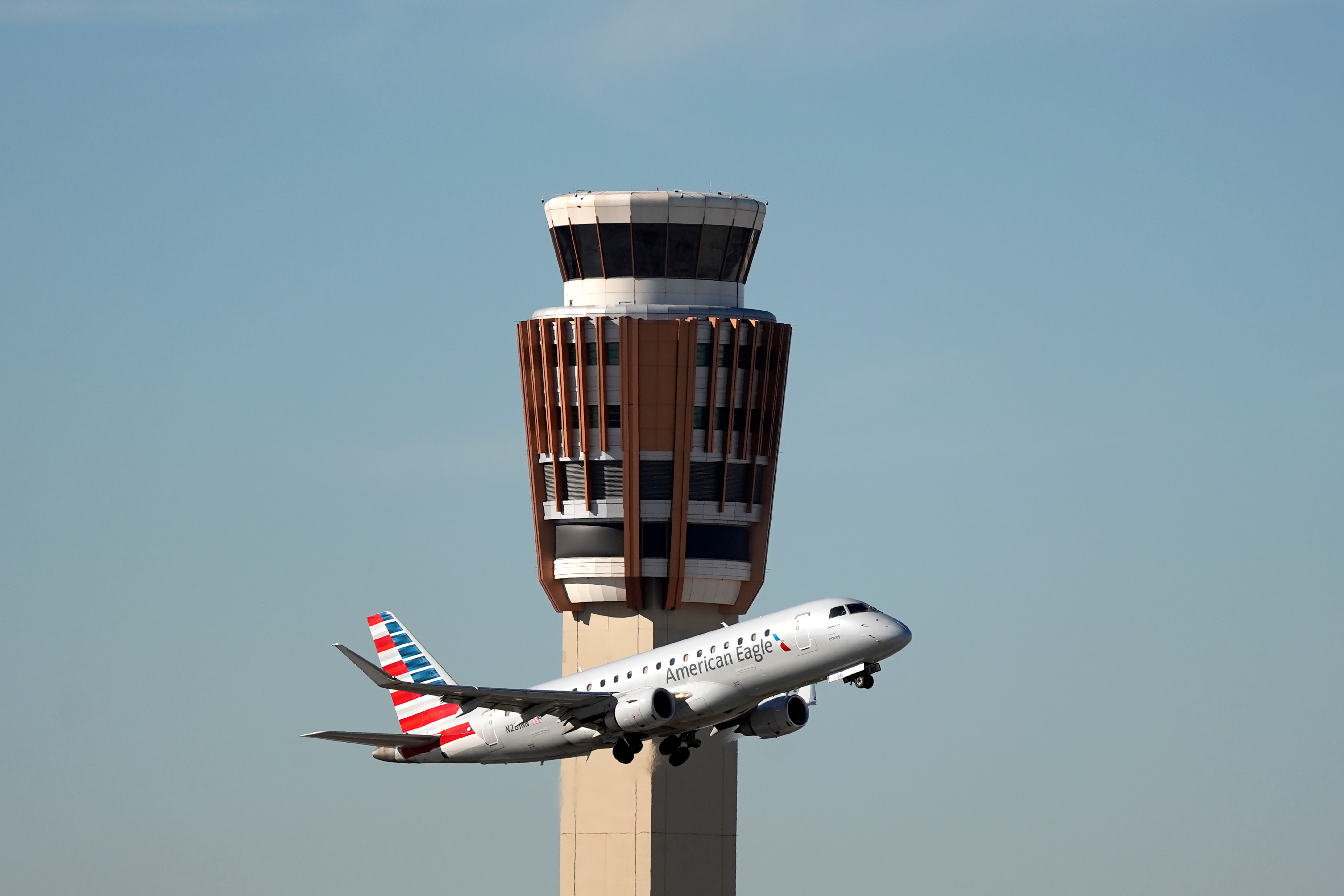 An American Airlines American Eagle jet flies past the air traffic control tower at Phoenix Sky Harbor International Airport Saturday, Nov. 8, 2025, in Phoenix.