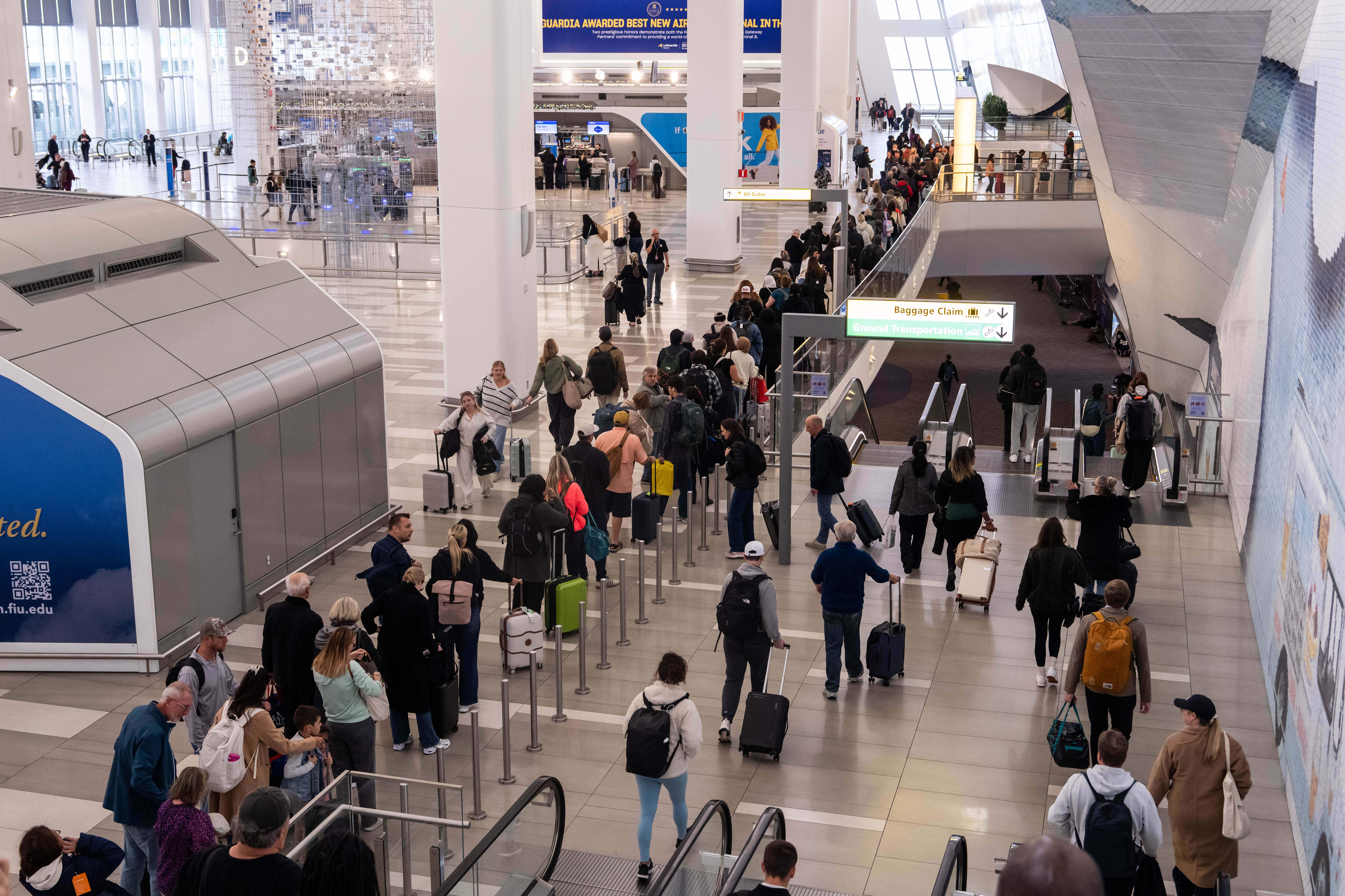 People wait in line at a Transportation Security Administration (TSA) security checkpoint at LaGuardia Airport (LGA) in the Queens borough of New York, Sunday, Nov. 9, 2025.