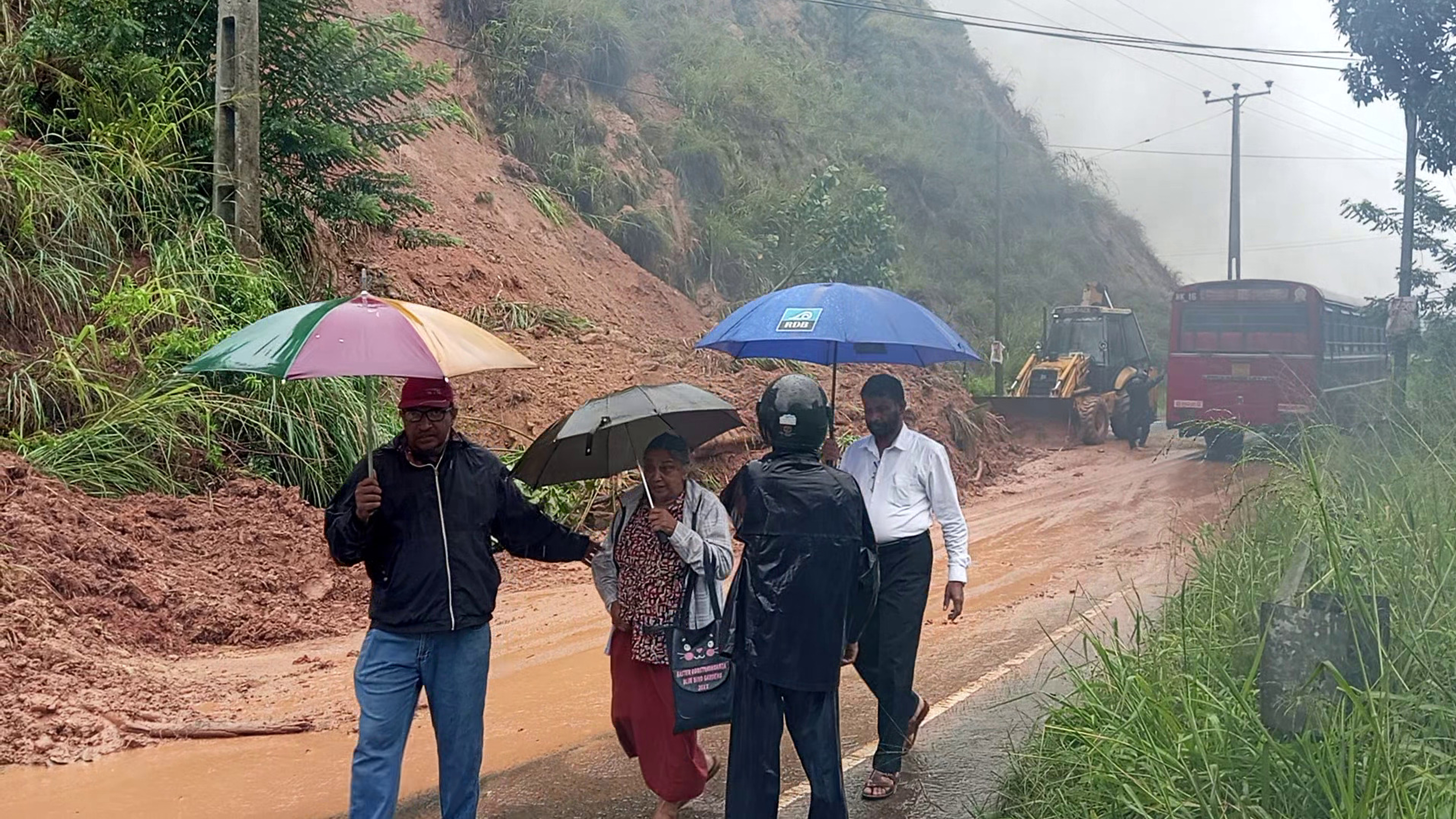 People walk past a section of a highway blocked by a landslide caused by heavy rain in Badulla, Sri Lanka, Thursday, Nov, 27, 2025